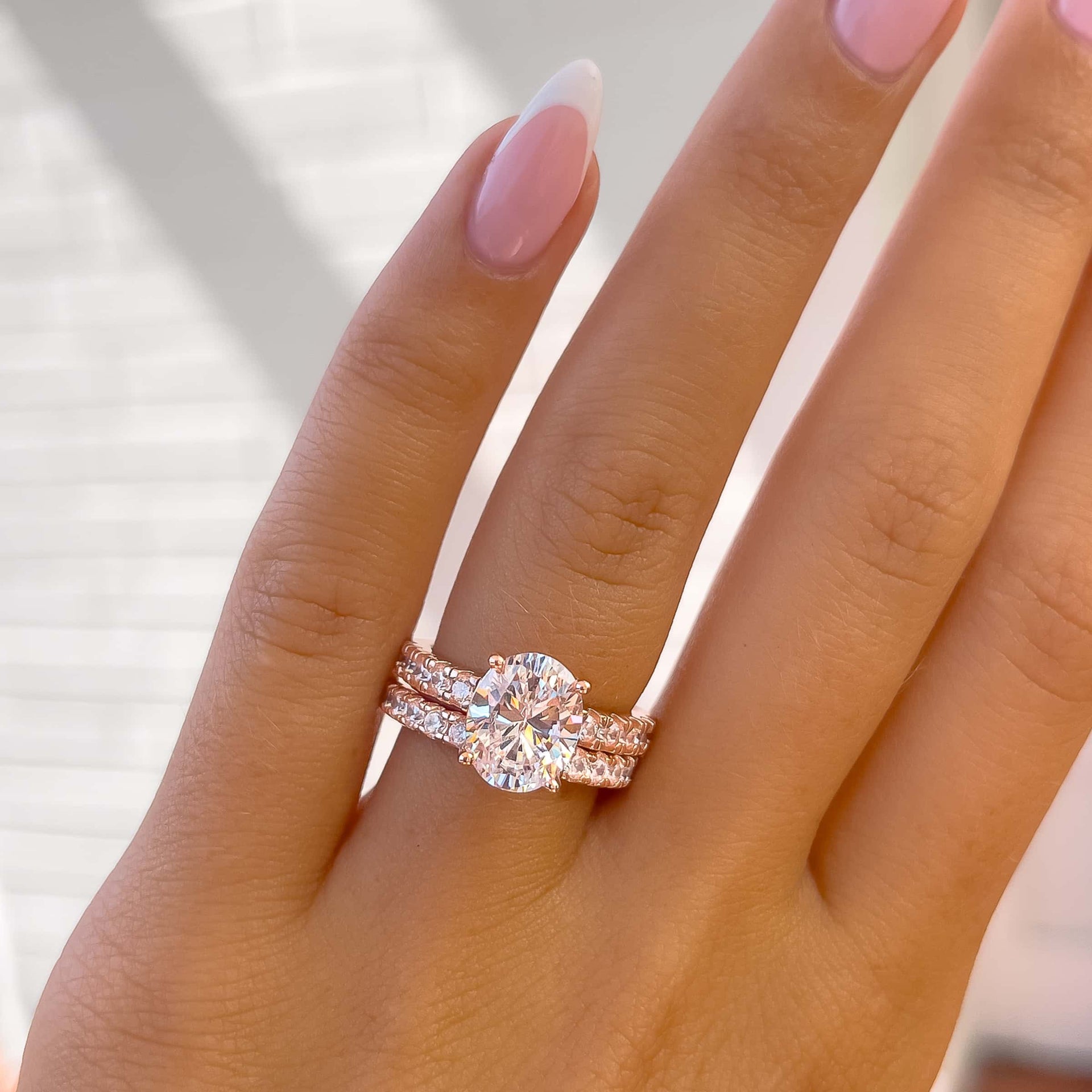 stunning 3 carat rose gold oval cut wedding ring set worn by model with french tip nails