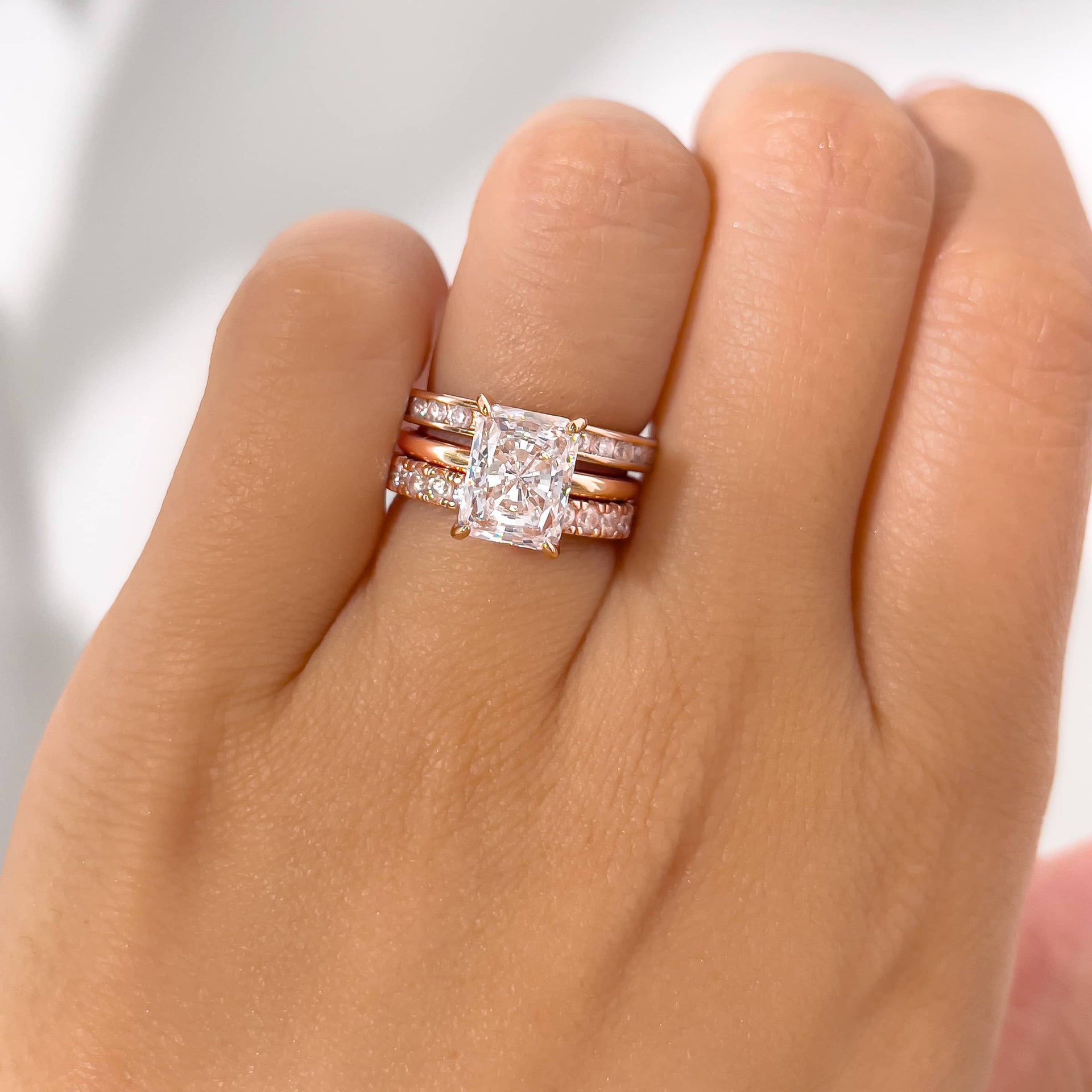 unique and bold rose gold triple wedding ring stack featuring a radiant cut solitaire and two wedding bands