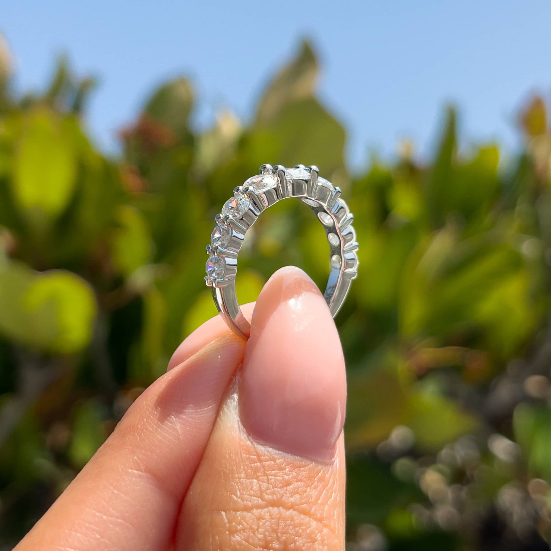 alternate view of a unique silver bold wedding band on model with neutral nails in front of greenery