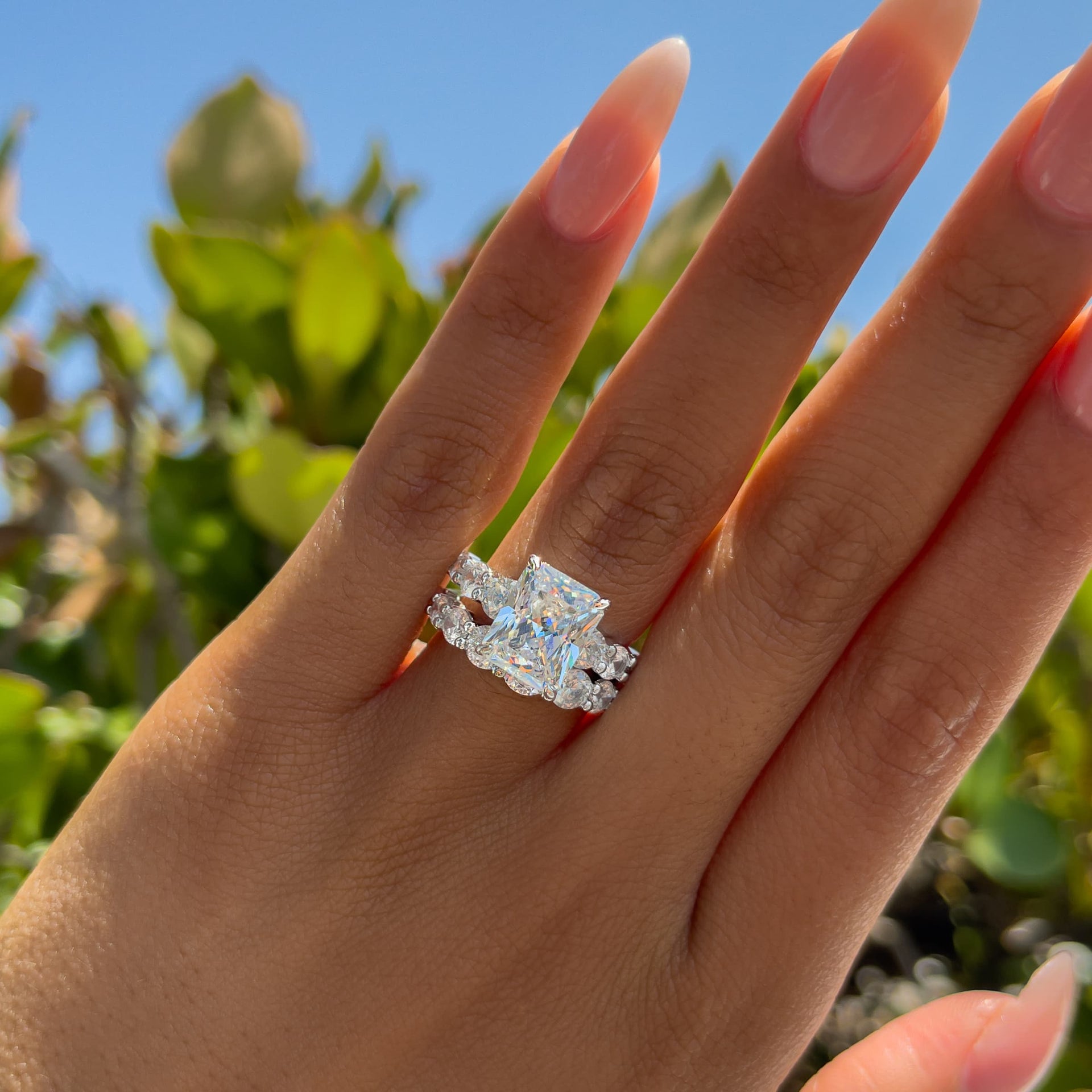 silver bold affordable radiant cut wedding ring set on model with neutral nails who is outside