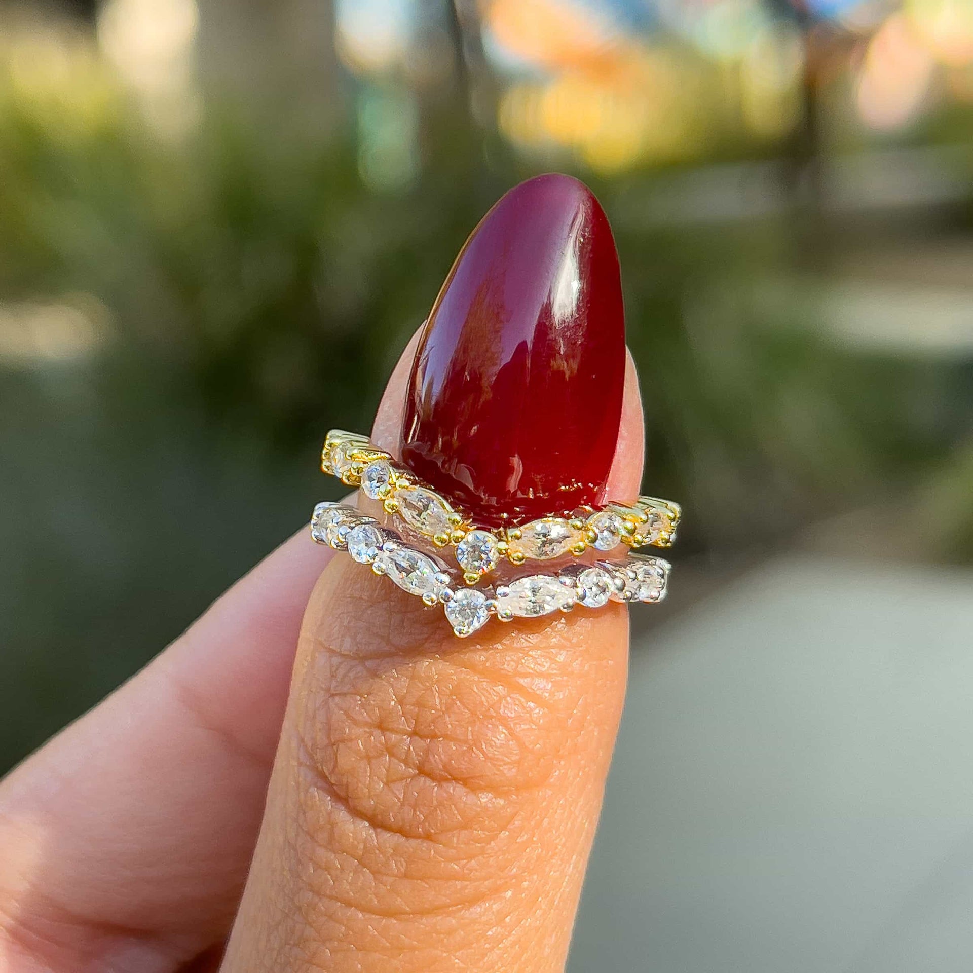 vintage style half eternity chevron band shown in gold and silver on model with deep red nails