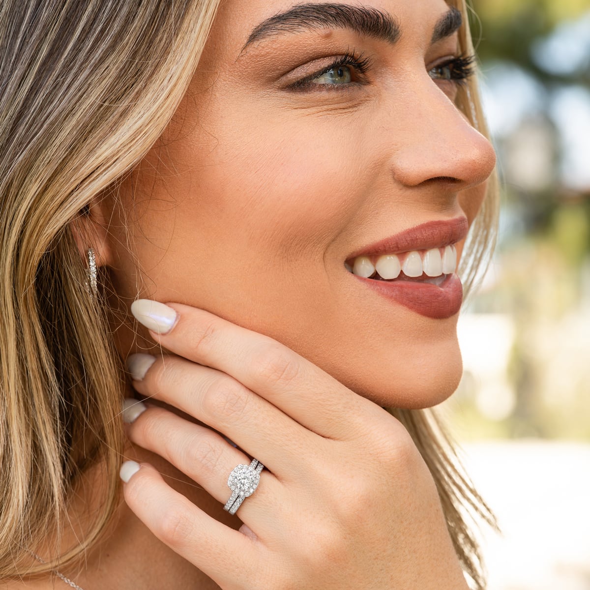 Woman smiling and wearing The Evermore silver wedding ring set with 1.5 carat round-cut simulated diamond in cushion halo and pavé band