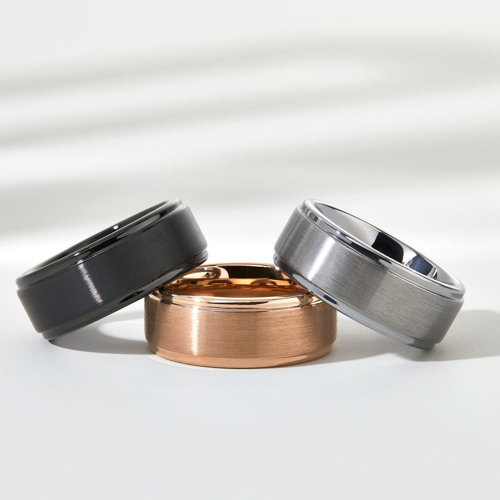 flatlay of black, rose gold, silver wedding band