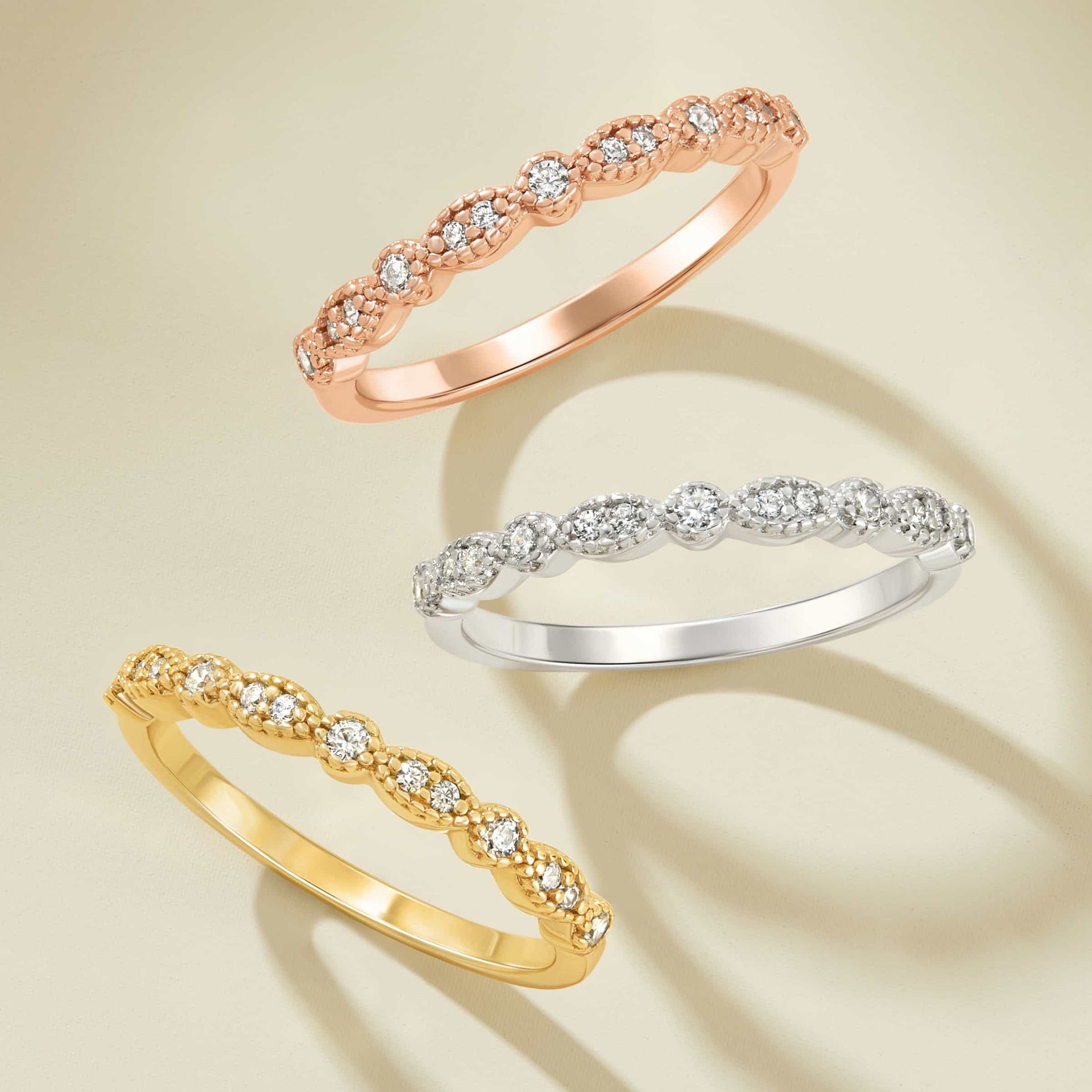 vintage rose gold, silver, and gold wedding bands on cream background in a row