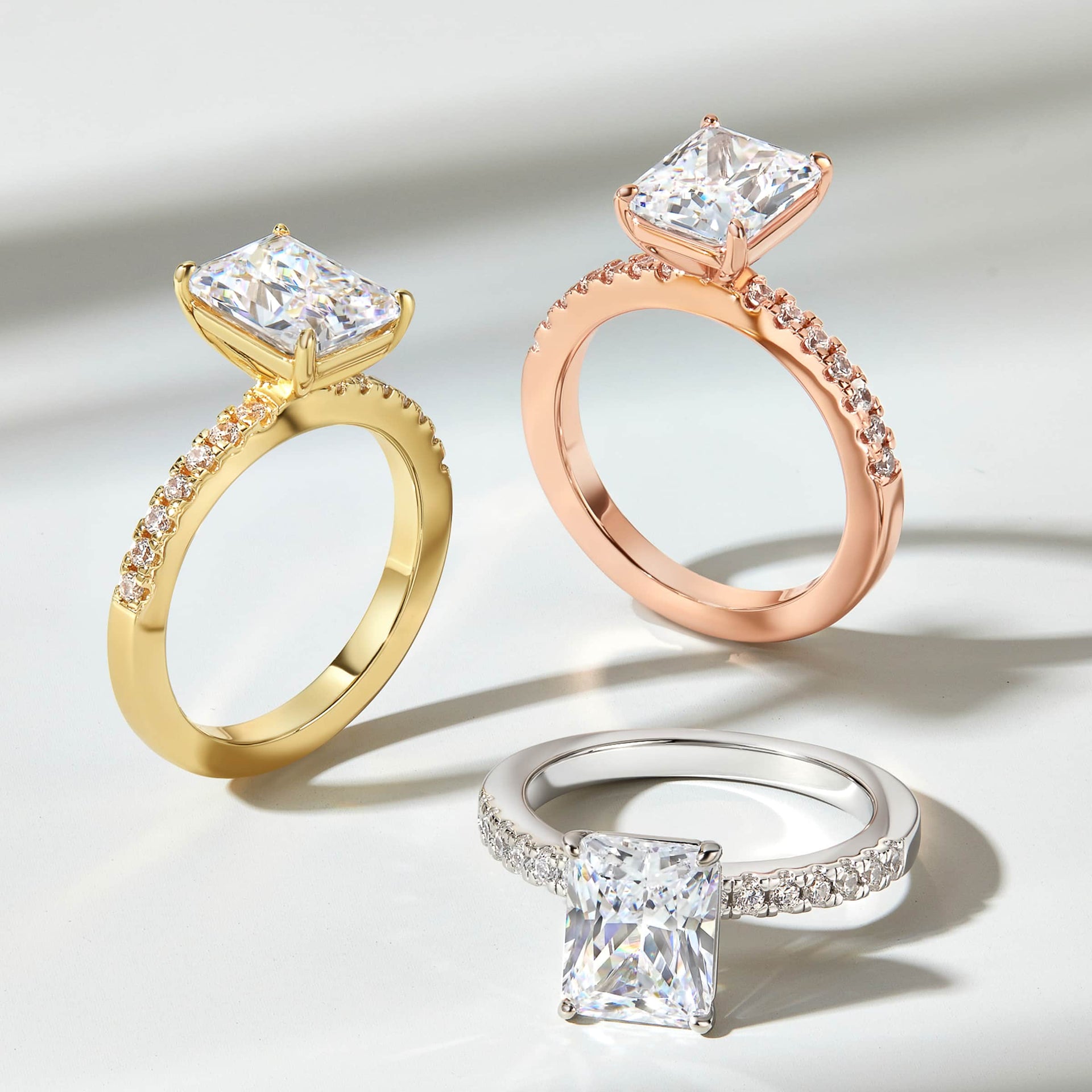 Brilliant 3 carat radiant cut engagement ring with half eternity band shown in gold, rose gold, and silver variants