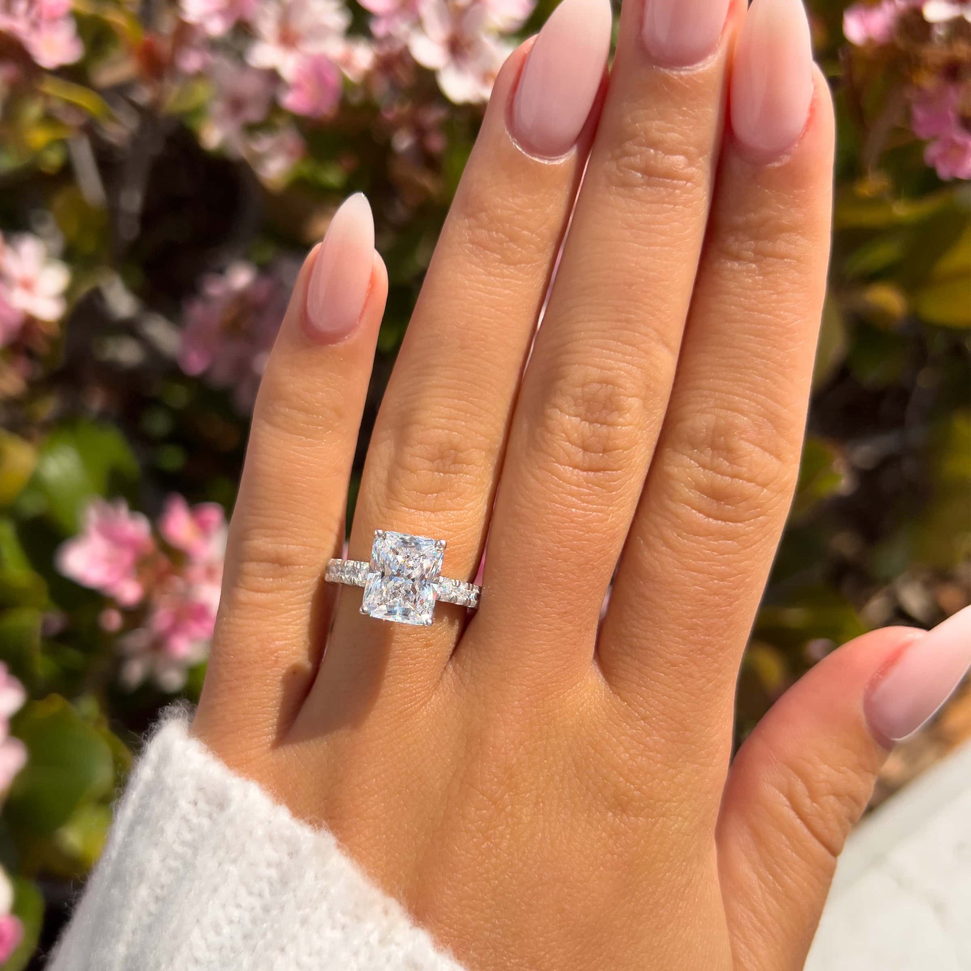 stunning silver 3.75 carat radiant cut engagement ring on model with neutral nails and white sleeve