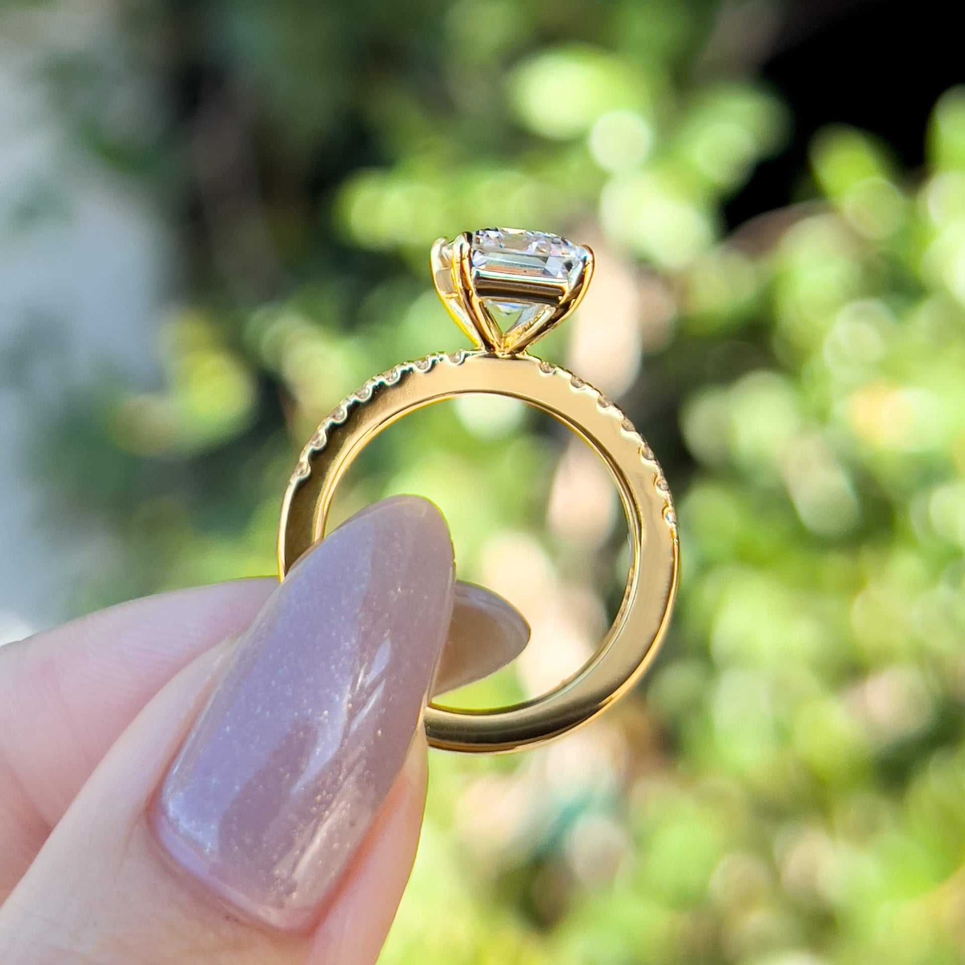 side view of gold 3 carat emerald cut engagement ring with half eternity band detailing