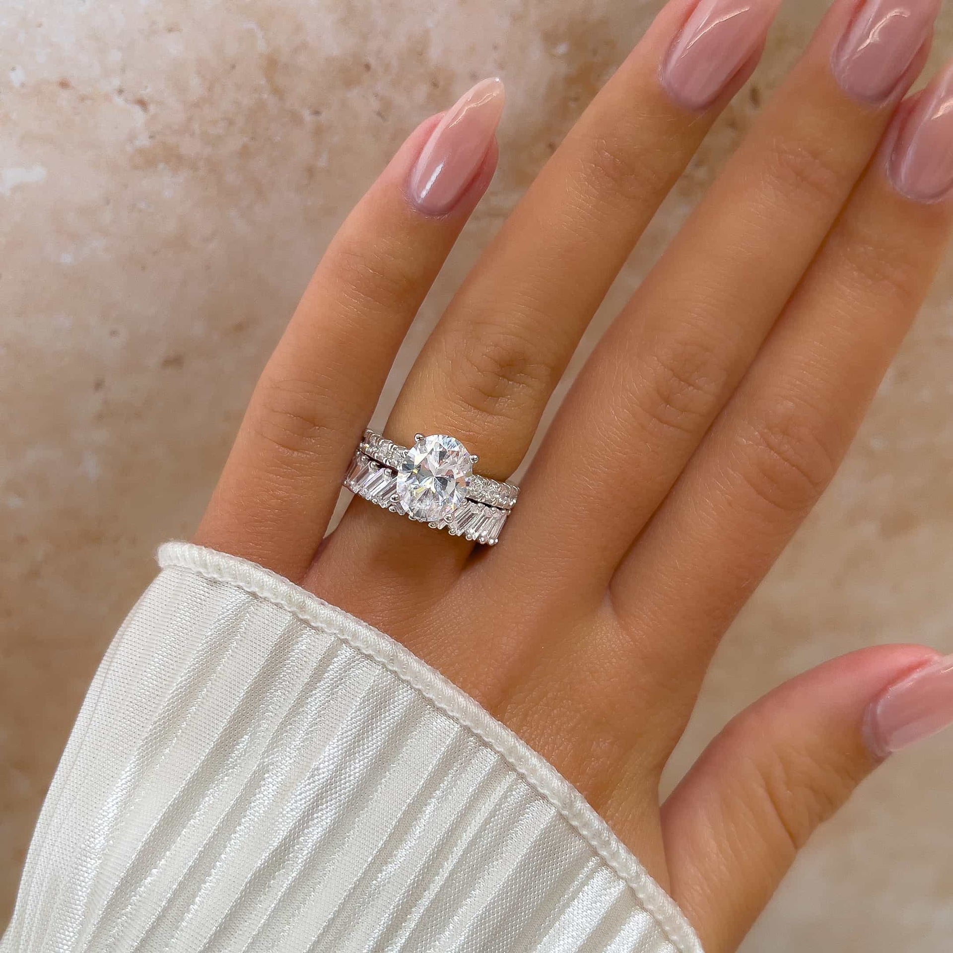 stunning 3 carat silver oval cut engagement ring with silver baguette wedding band on model's hand