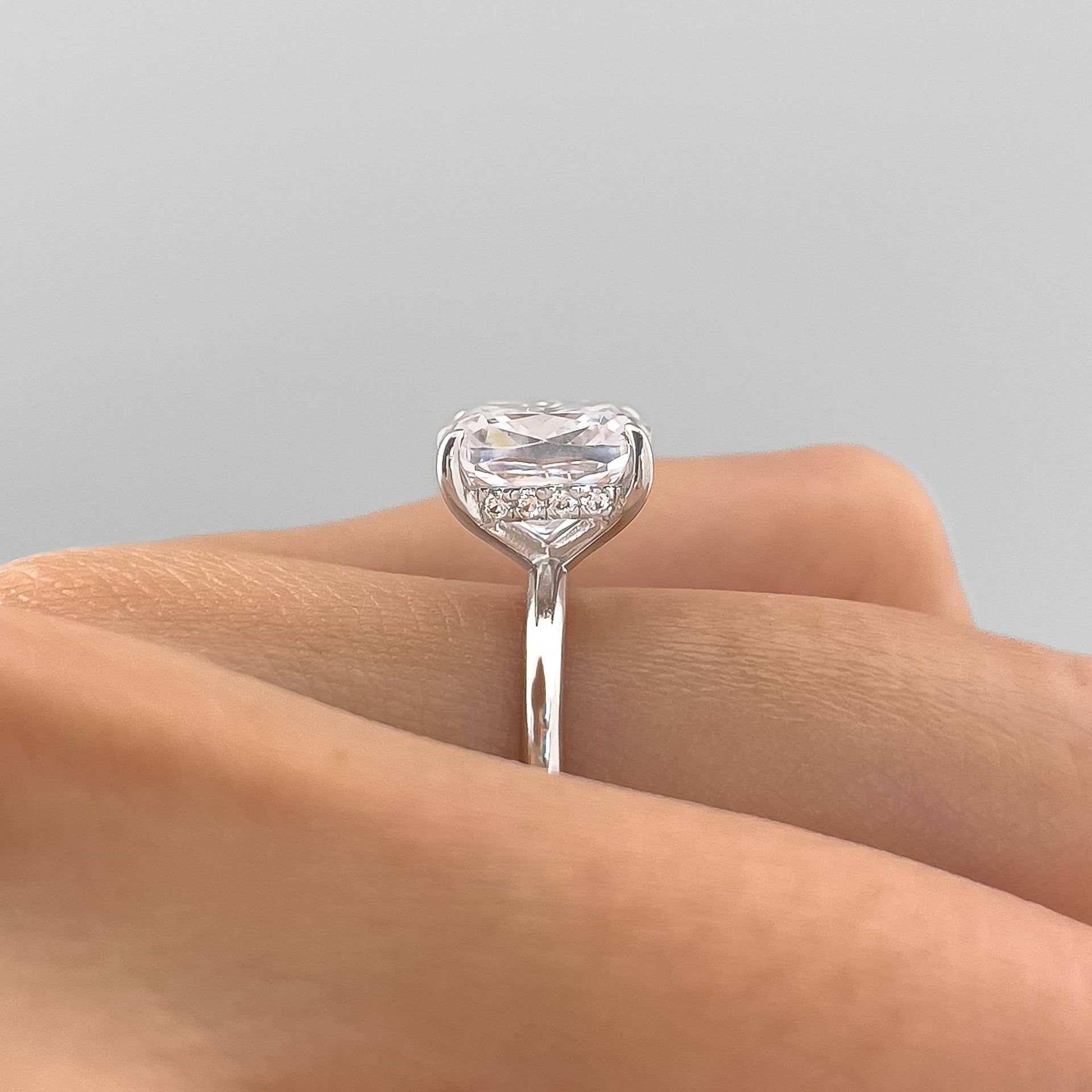 Side view of The Claire silver engagement ring with 3.5 carat cushion-cut simulated diamond and hidden halo setting on white background