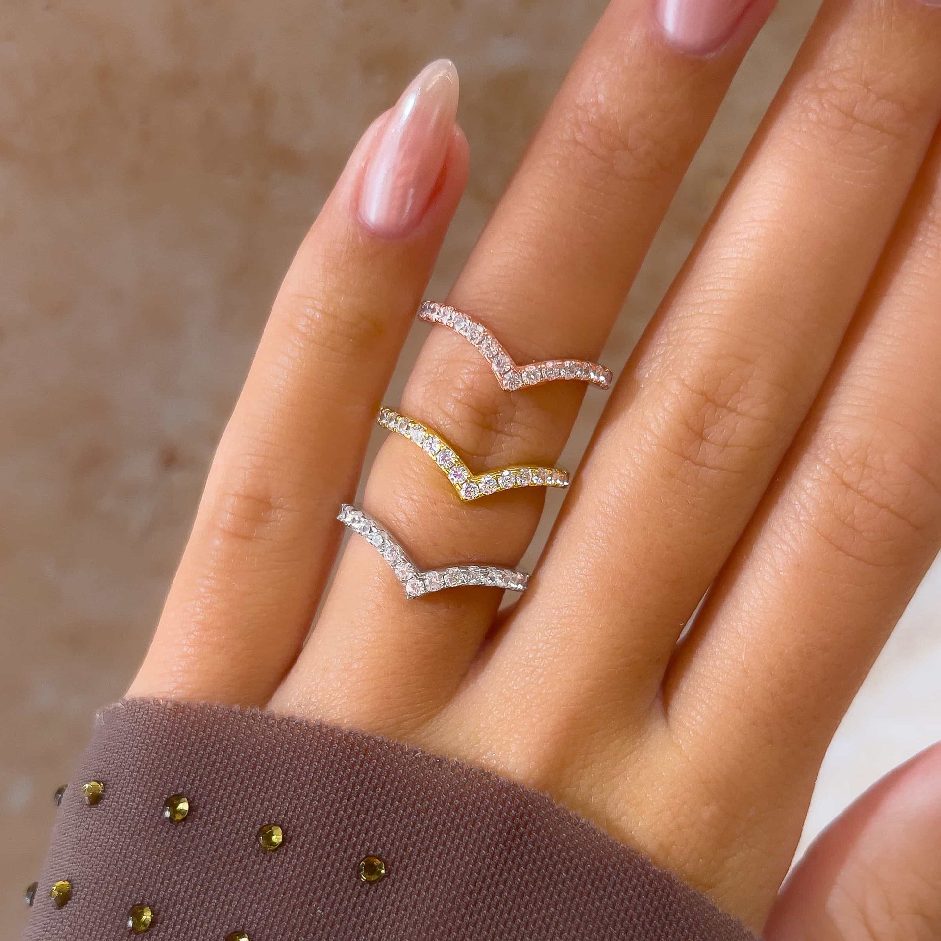 stunning chevron gold, silver, and rose gold wedding bands on model's hand with pink nails and purple sleeve