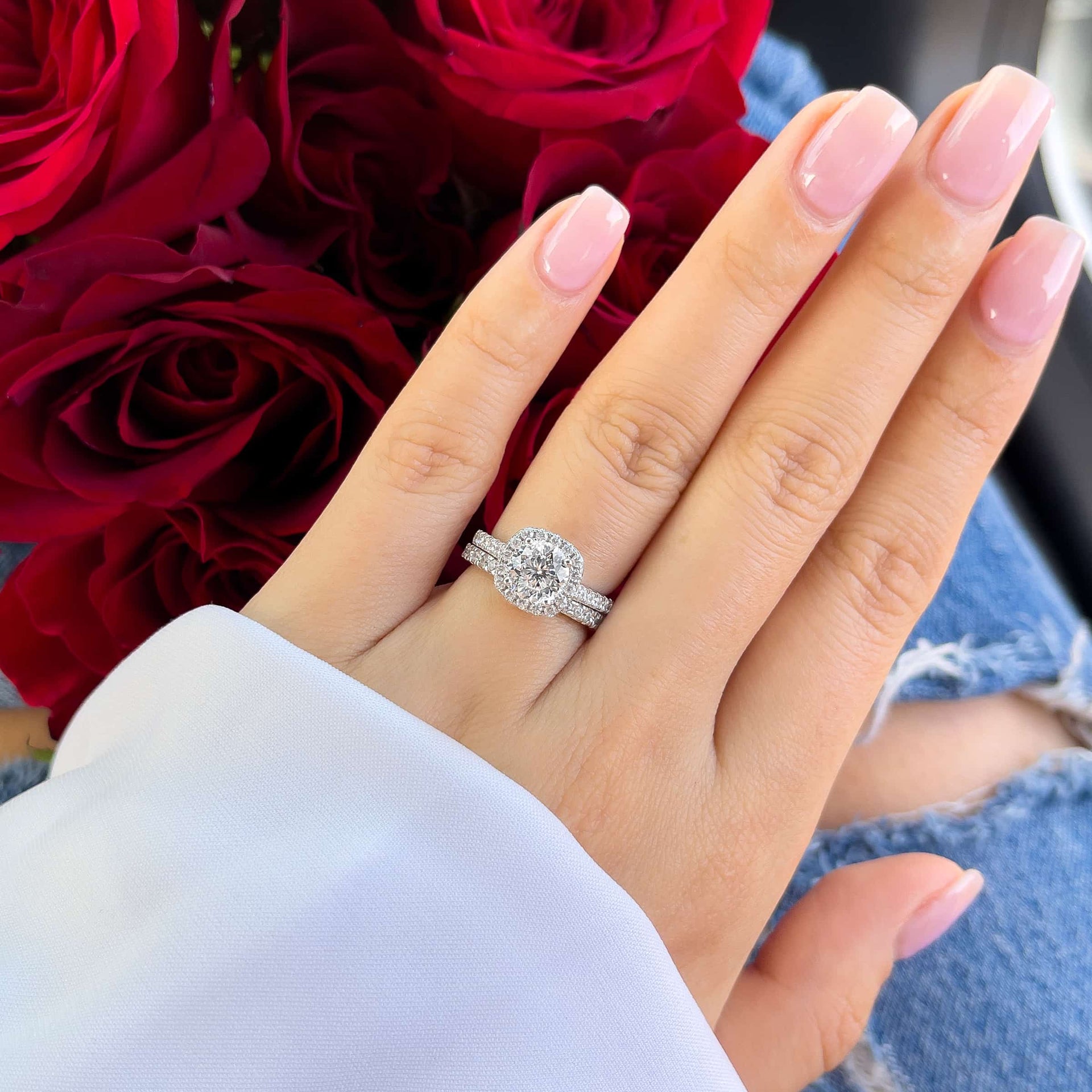 The Evermore silver wedding ring set with 1.5 carat round-cut simulated diamond in cushion halo and pavé band, worn with glossy pink nails