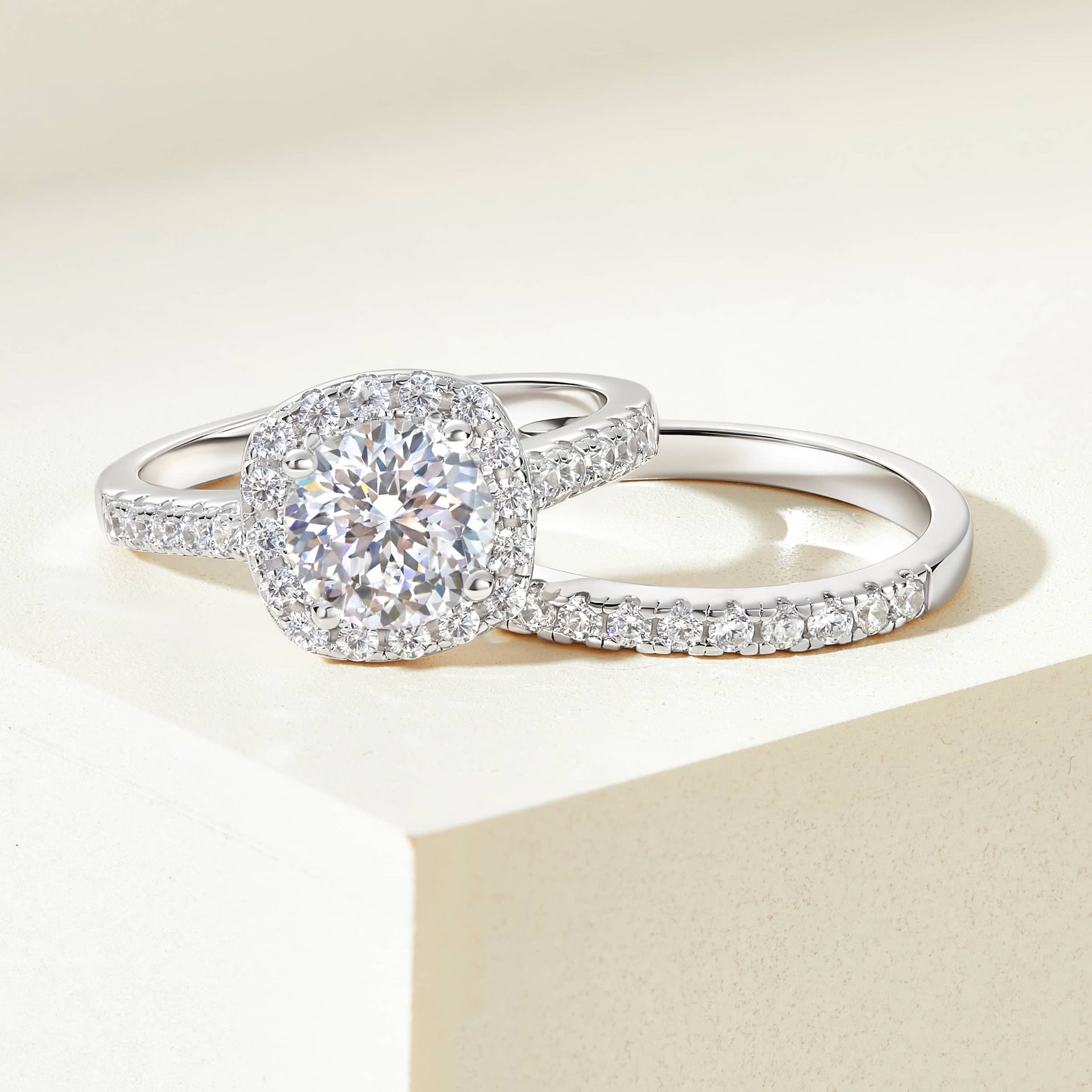 Flat lay of The Evermore silver engagement ring set with 1.5 carat round-cut simulated diamond in a cushion halo and half eternity wedding band on white background