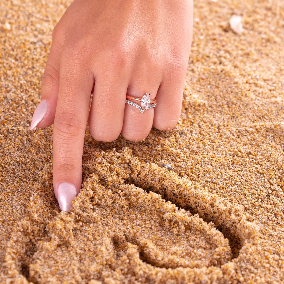 drawing in the sand wearing rose gold wedding rings