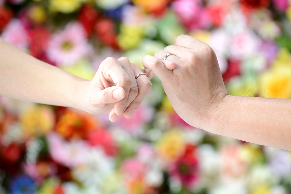 Hands wearing wedding bands doing a pinky promise