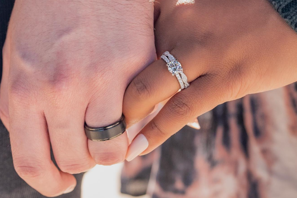 man with tungsten ring holding hands with woman wearing wedding set