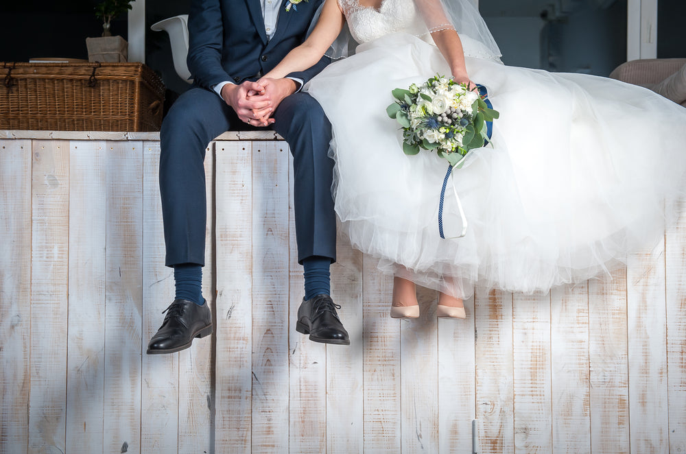 Bride and groom sitting down on a wall