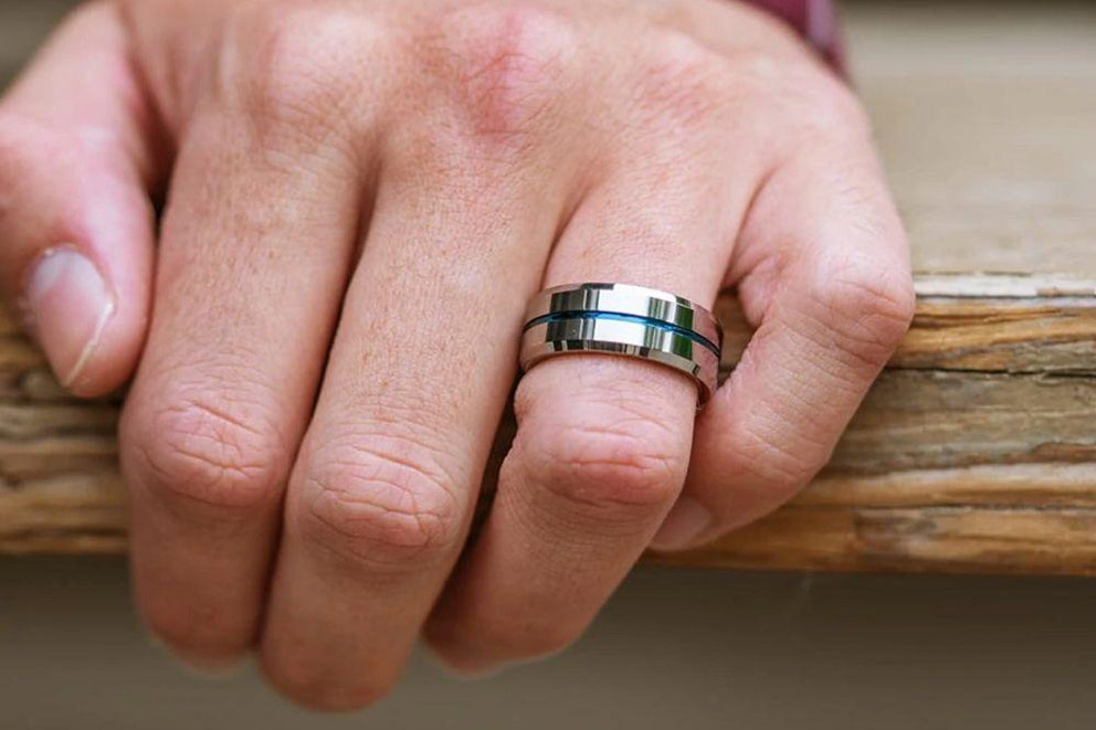 a man holding a wooden railing wearing the admiral wedding band