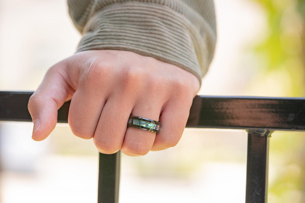 a close up of a man wearing a tungsten wedding band with his hand on a railing