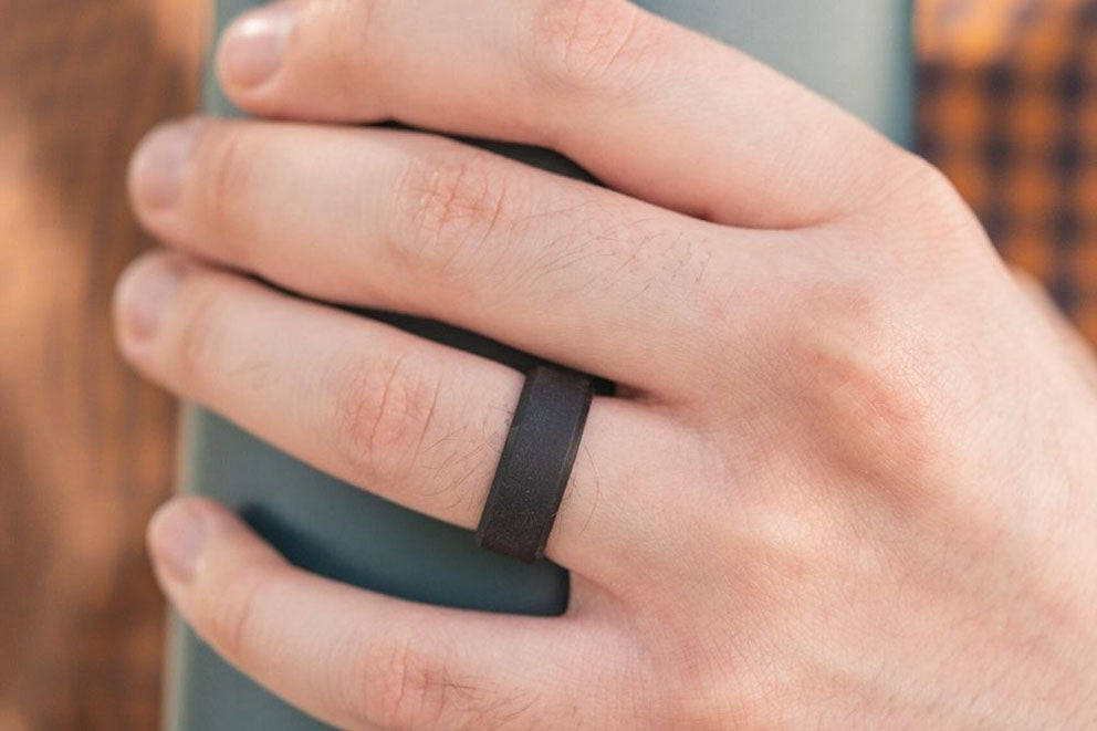 a man with a black wedding band holding a thermos