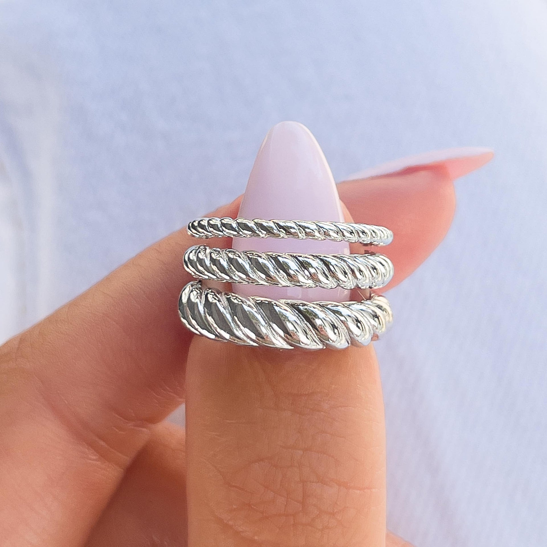 minimalist silver rings with twisting eternity detailing on model with light pink nails