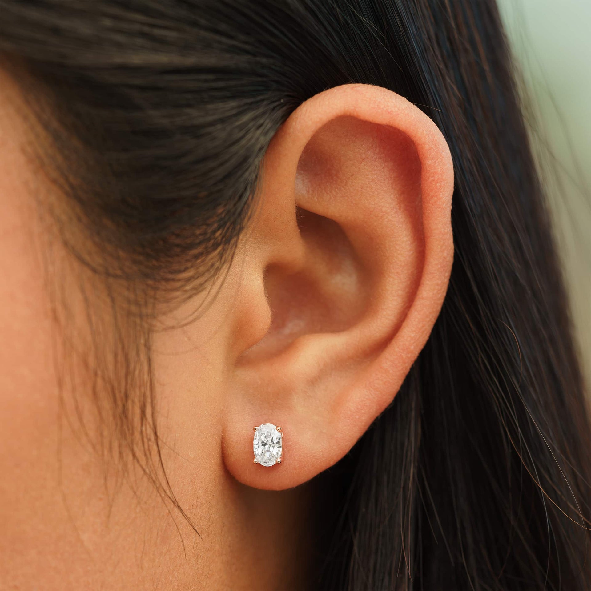 small rose gold oval cut stud earrings on female model