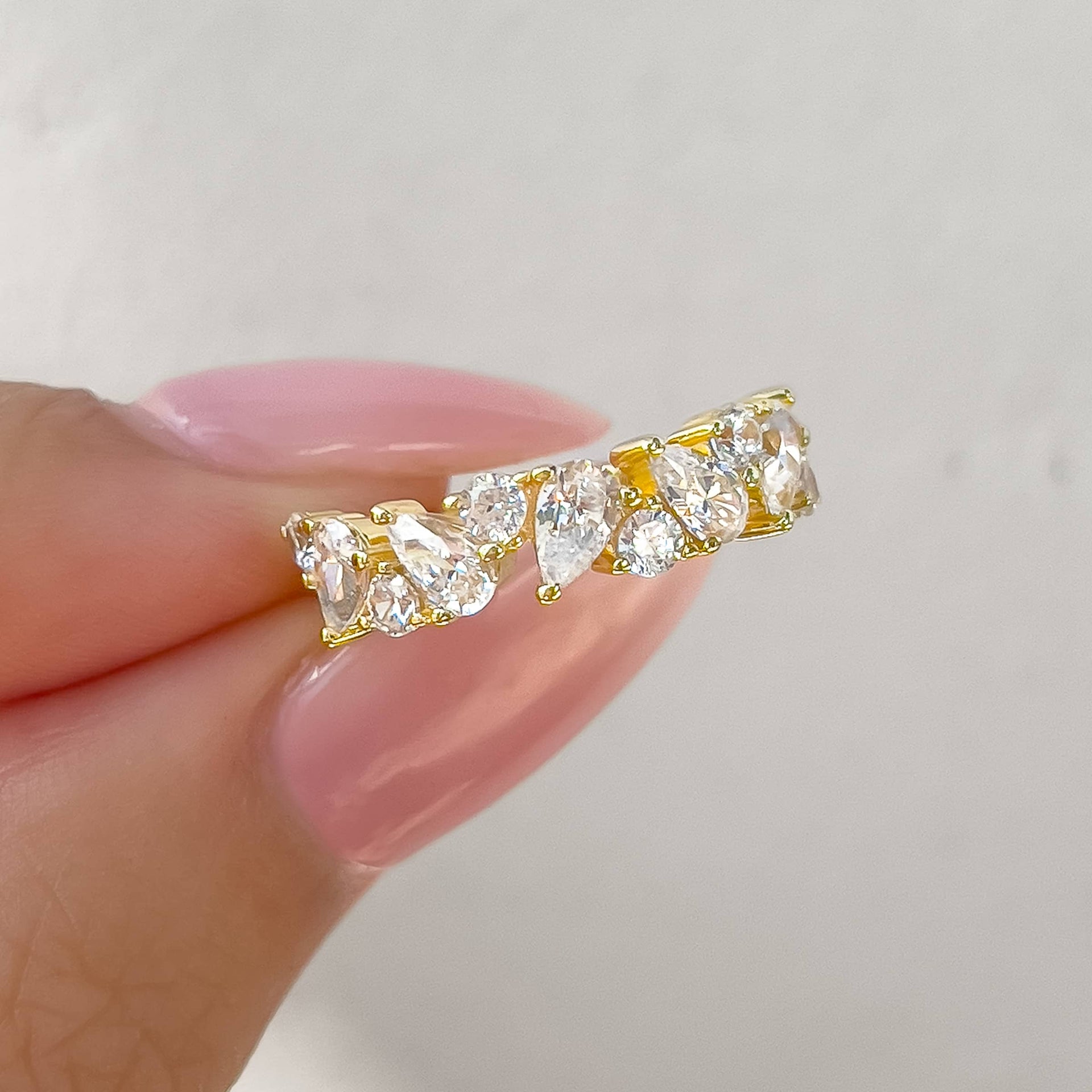 bold gold mixed cut half eternity band held by model with pink nails