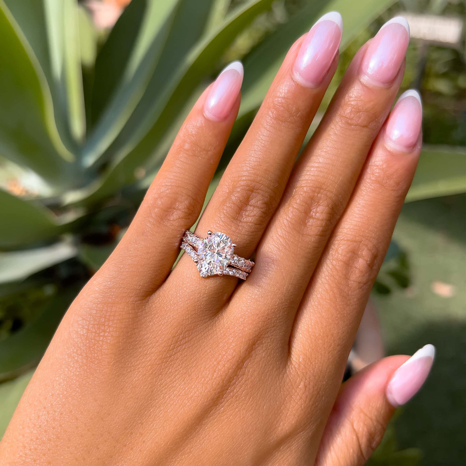 rose gold wedding ring set with oval cut engagement ring and chevron half eternity band worn by model