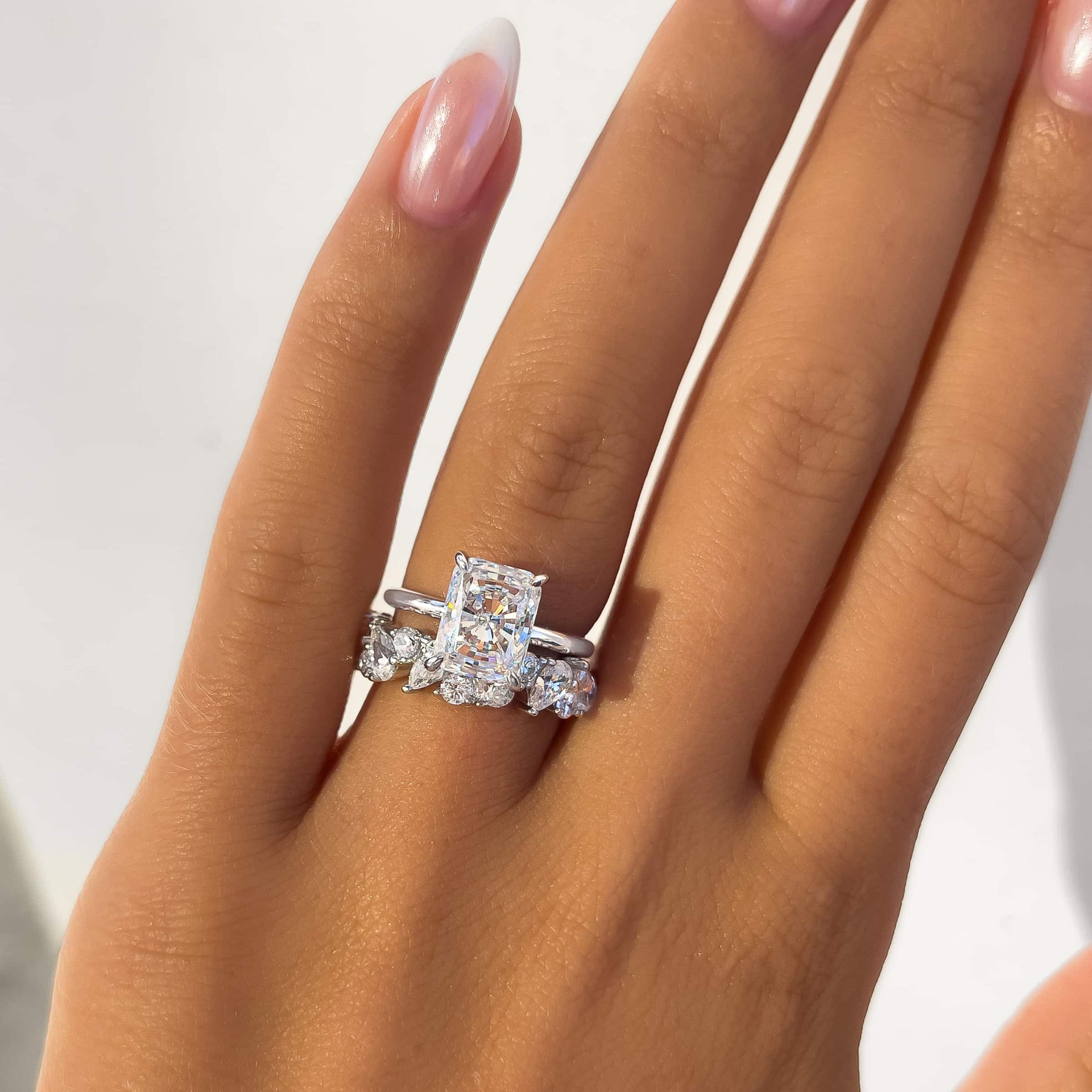 gorgeous silver 3 carat radiant cut solitaire engagement ring with bold, multi-cut wedding band on model with french tip nails