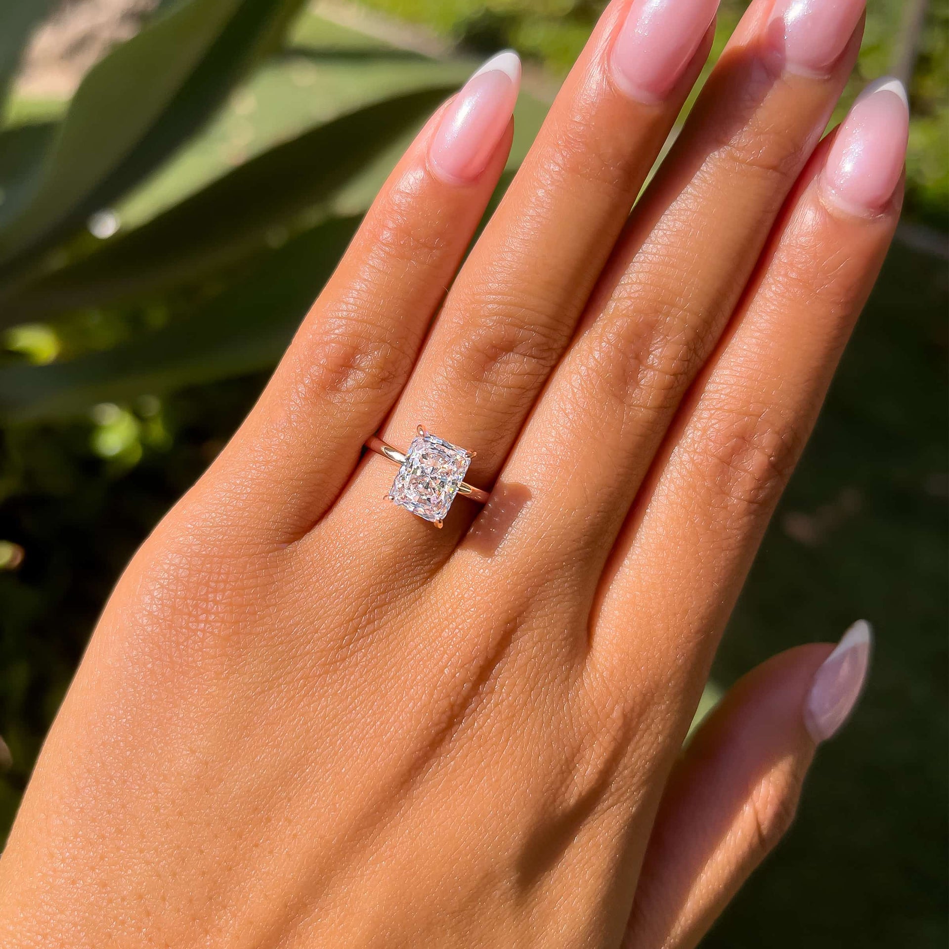 rose gold radiant cut solitaire engagement ring on model with french tip nails
