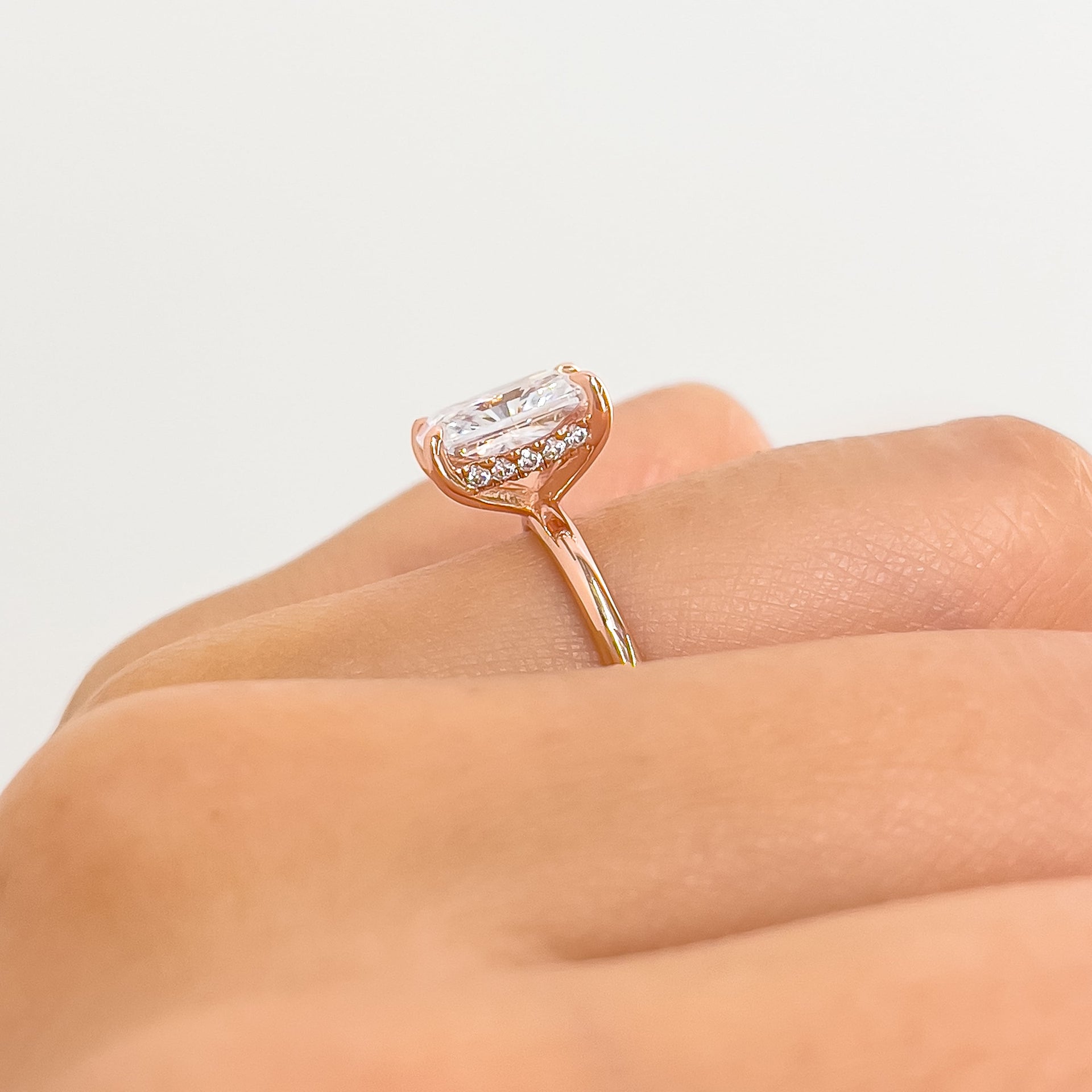 setting shot highlighting this rose gold radiant cut solitaire's hidden halo detail, worn on a model