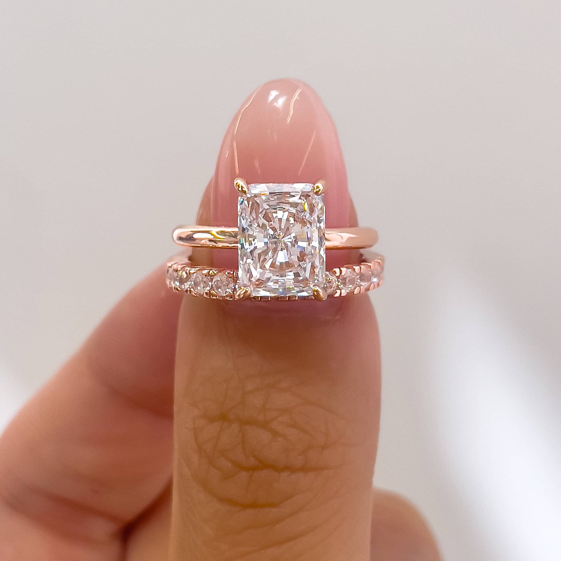 simple and classic rose gold radiant cut wedding ring set shown on model with neutral nails