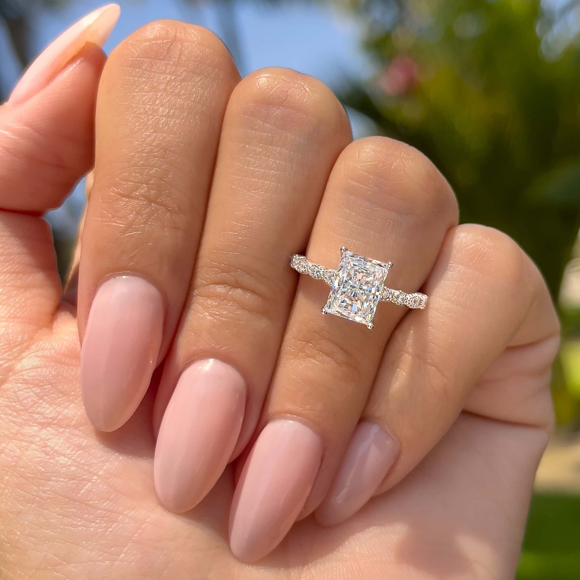 stunning silver 1.5 carat radiant cut engagement ring with vintage style detailing on model with neutral nails