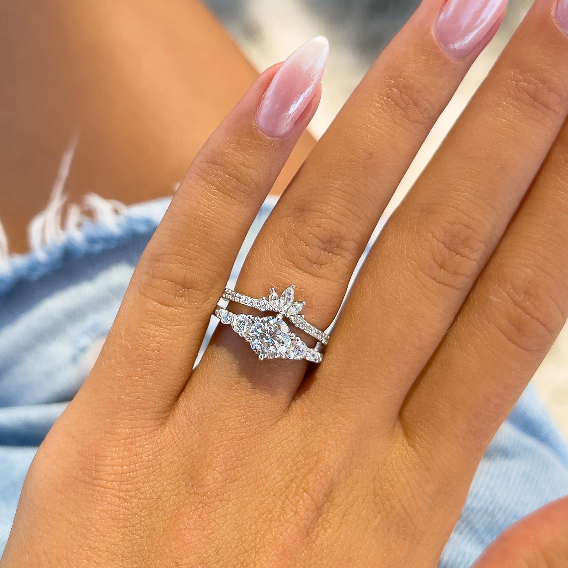 gorgeous silver wedding set featuring a vintage round cut engagement ring and vintage style band on model wearing denim shorts