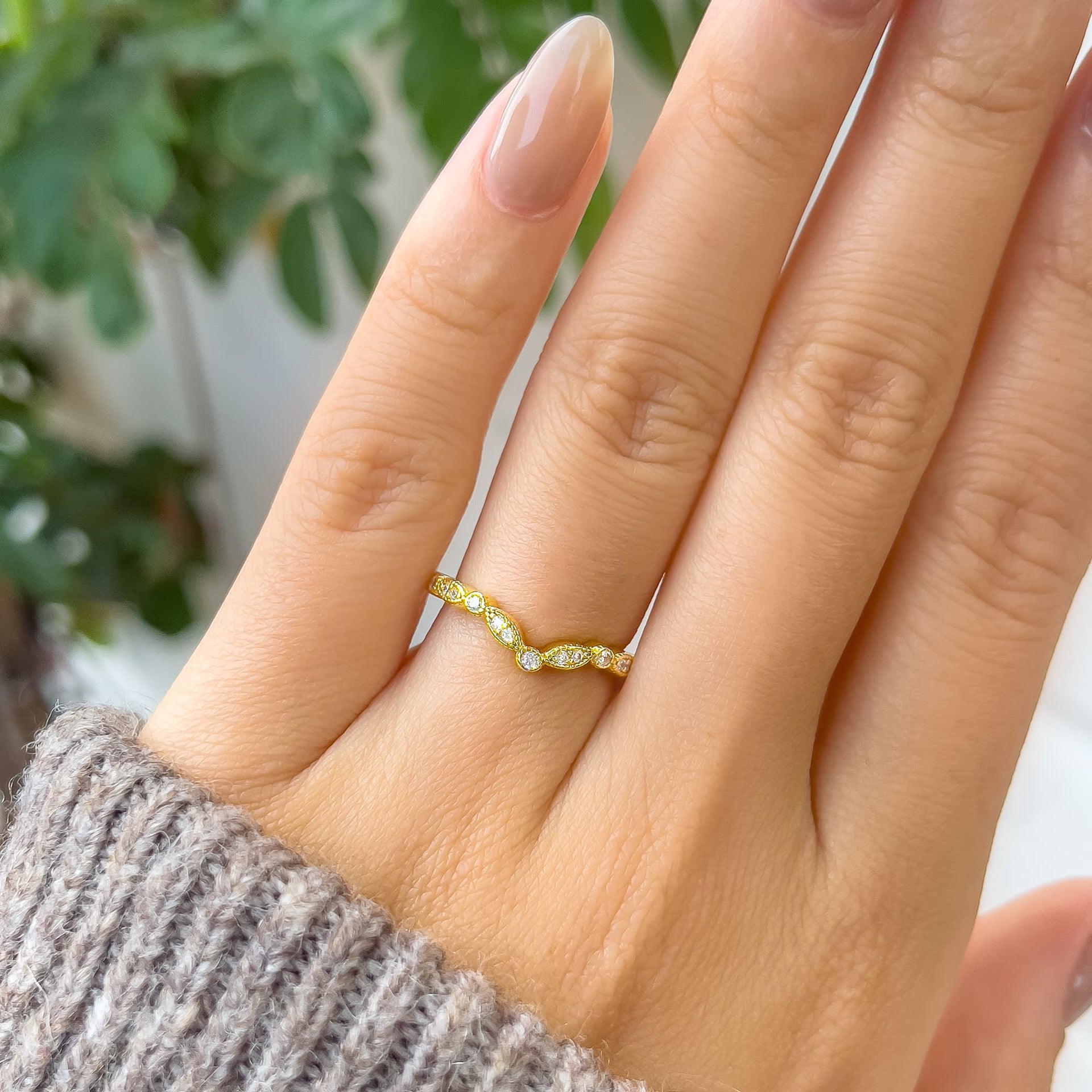 stunning gold chevron wedding band shown on model's hand with brown sweater sleeve and greenery in the background