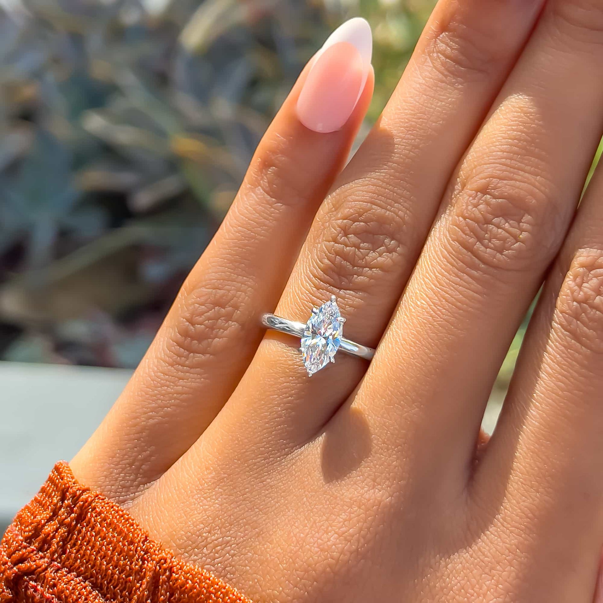 Shiny silver 1 carat marquise cut solitaire engagement ring on model with French tip nails