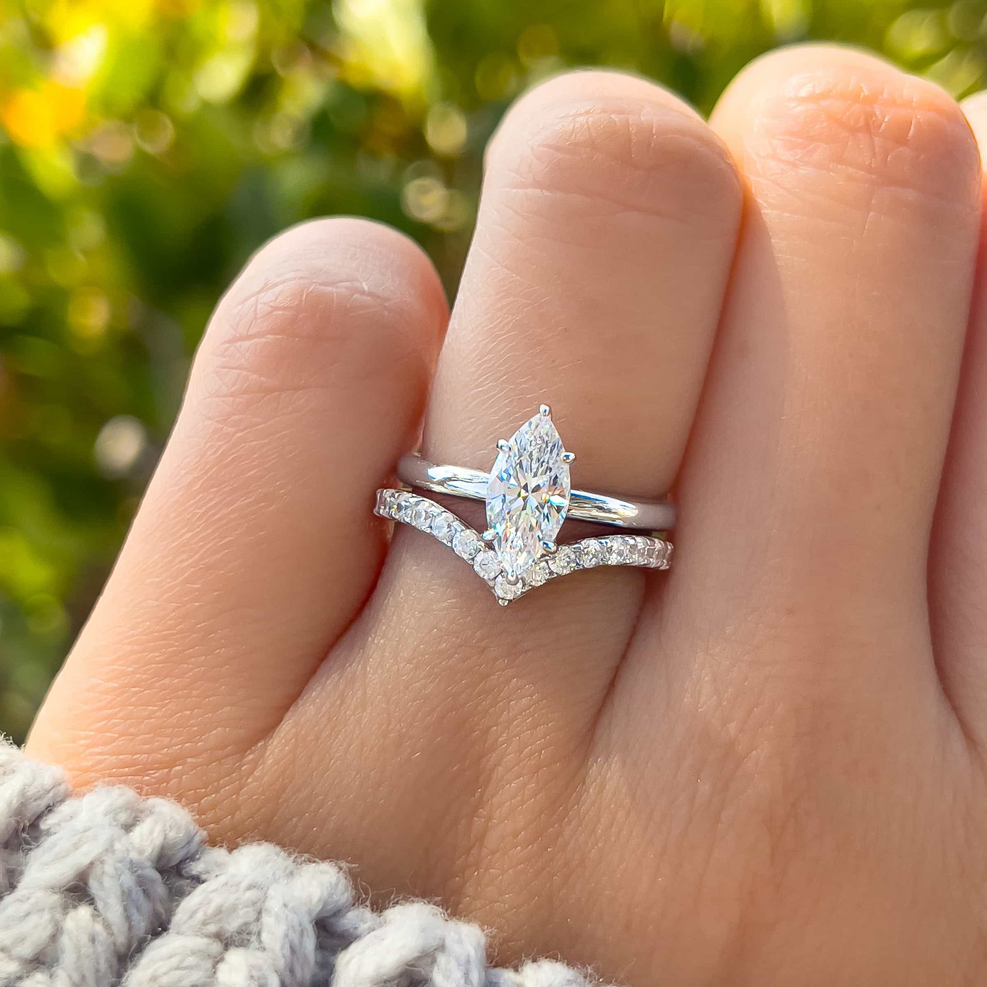 Silver wedding stack made of 1 carat marquise cut solitaire and chevron half eternity wedding band on model wearing a knit sweater