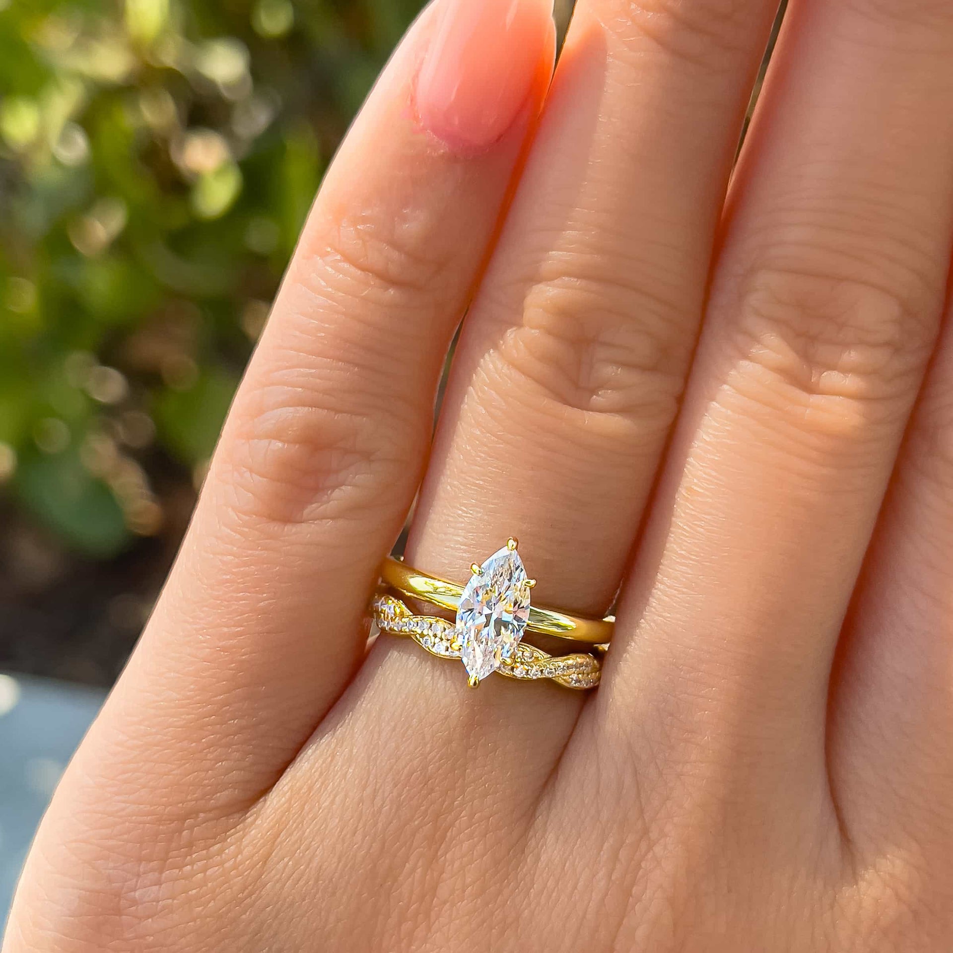 Gold wedding stack made of 1 carat marquise cut solitaire and a twisting detail eternity wedding band on model 