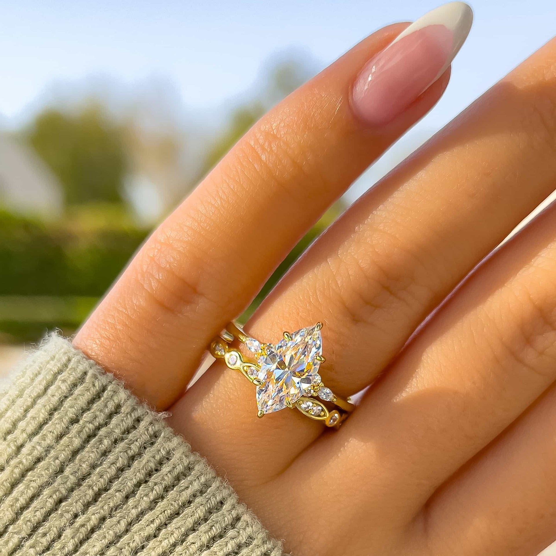 stunning vintage wedding ring set made of a marquis cut engagement ring and unique vintage wedding band on model with french tip nails and green sweater