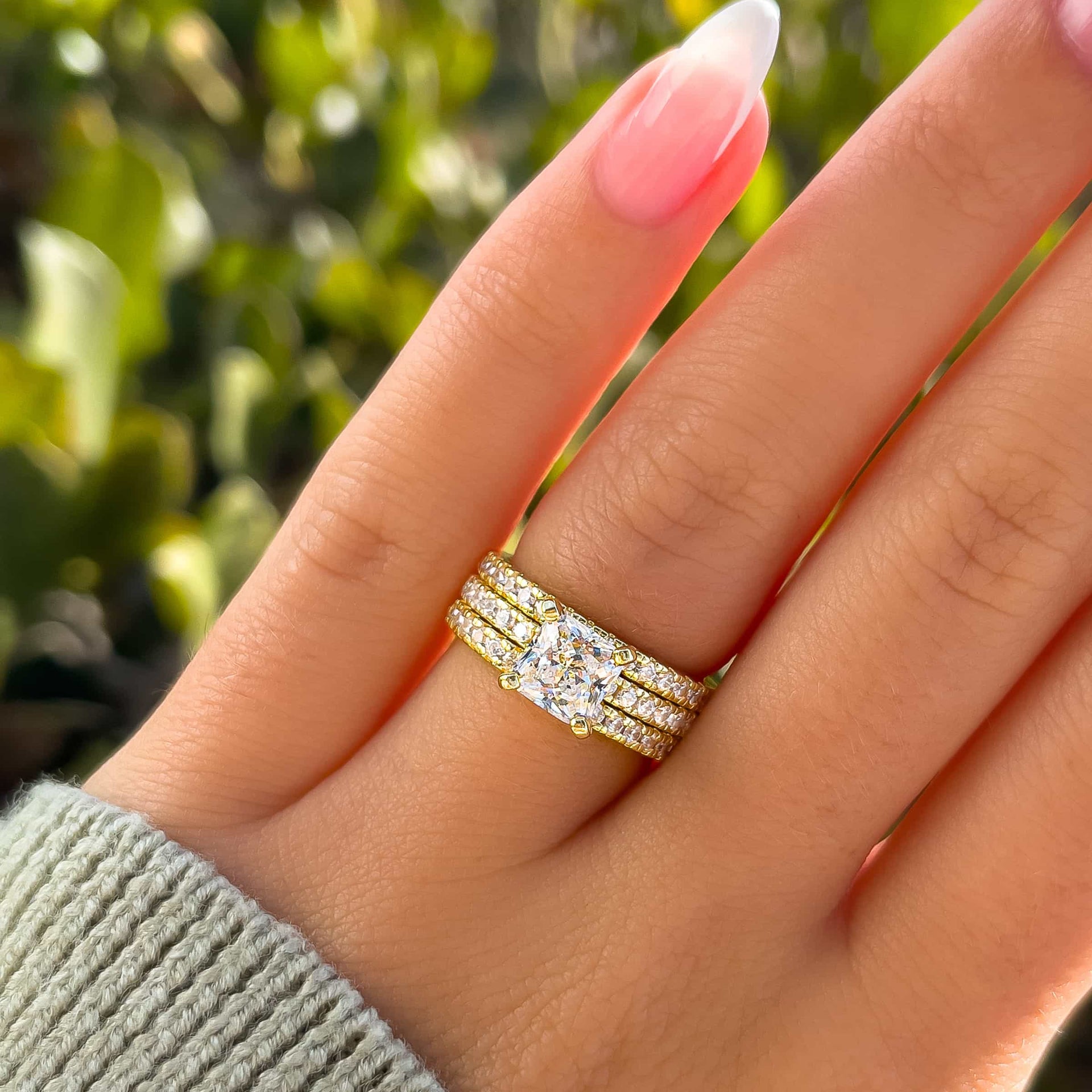 stunning and simple gold triple wedding ring stack on model with french tip nails and green sweater