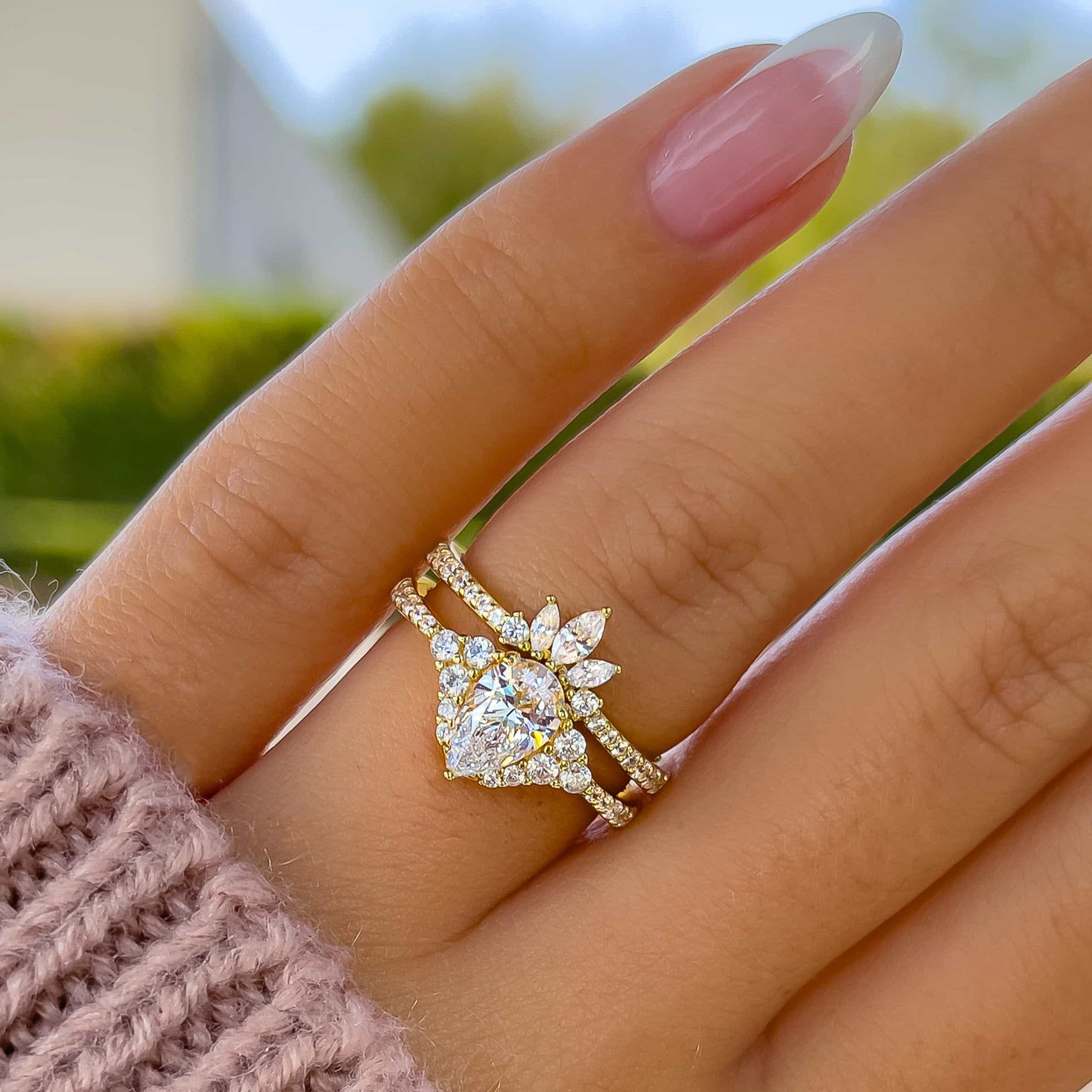 stunning gold vintage 1 carat pear cut wedding ring set on model with french tip nails and pink knit sweater