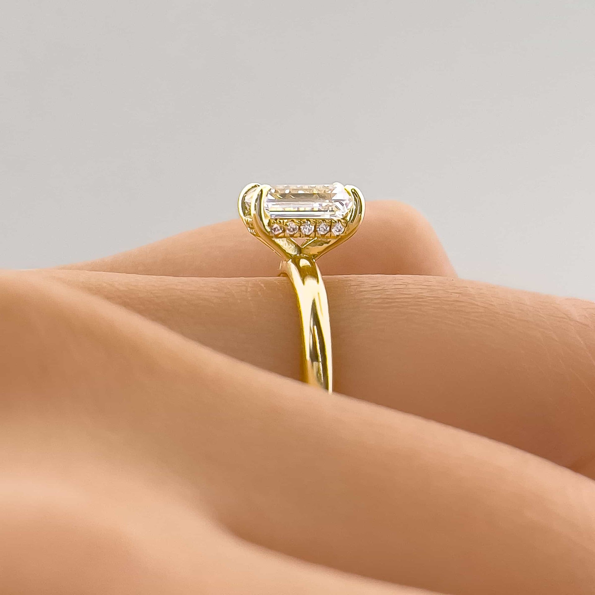 setting shot close up of gold emerald cut solitaire engagement ring