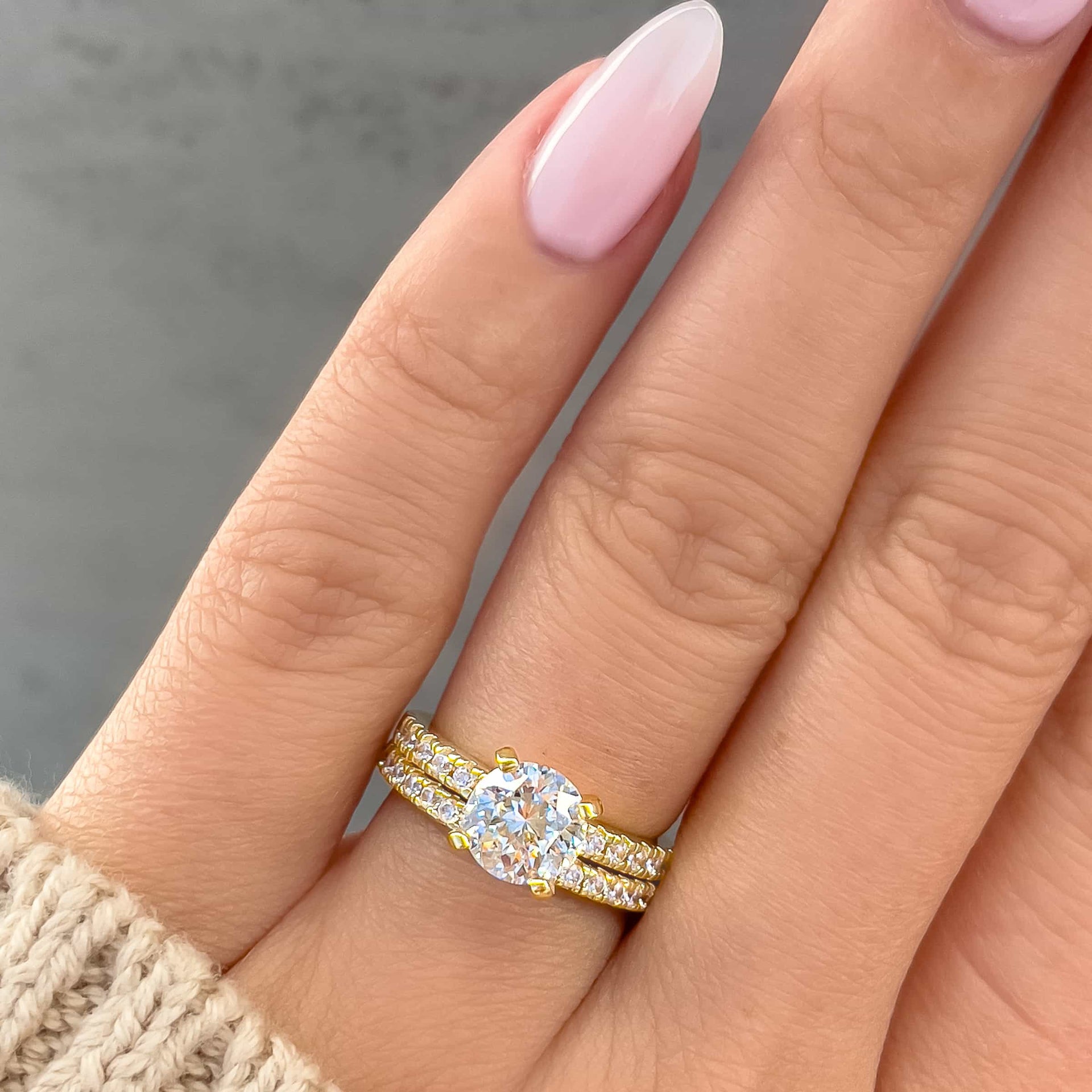 round cut half eternity wedding ring set on model with light pink nails and tan sweater