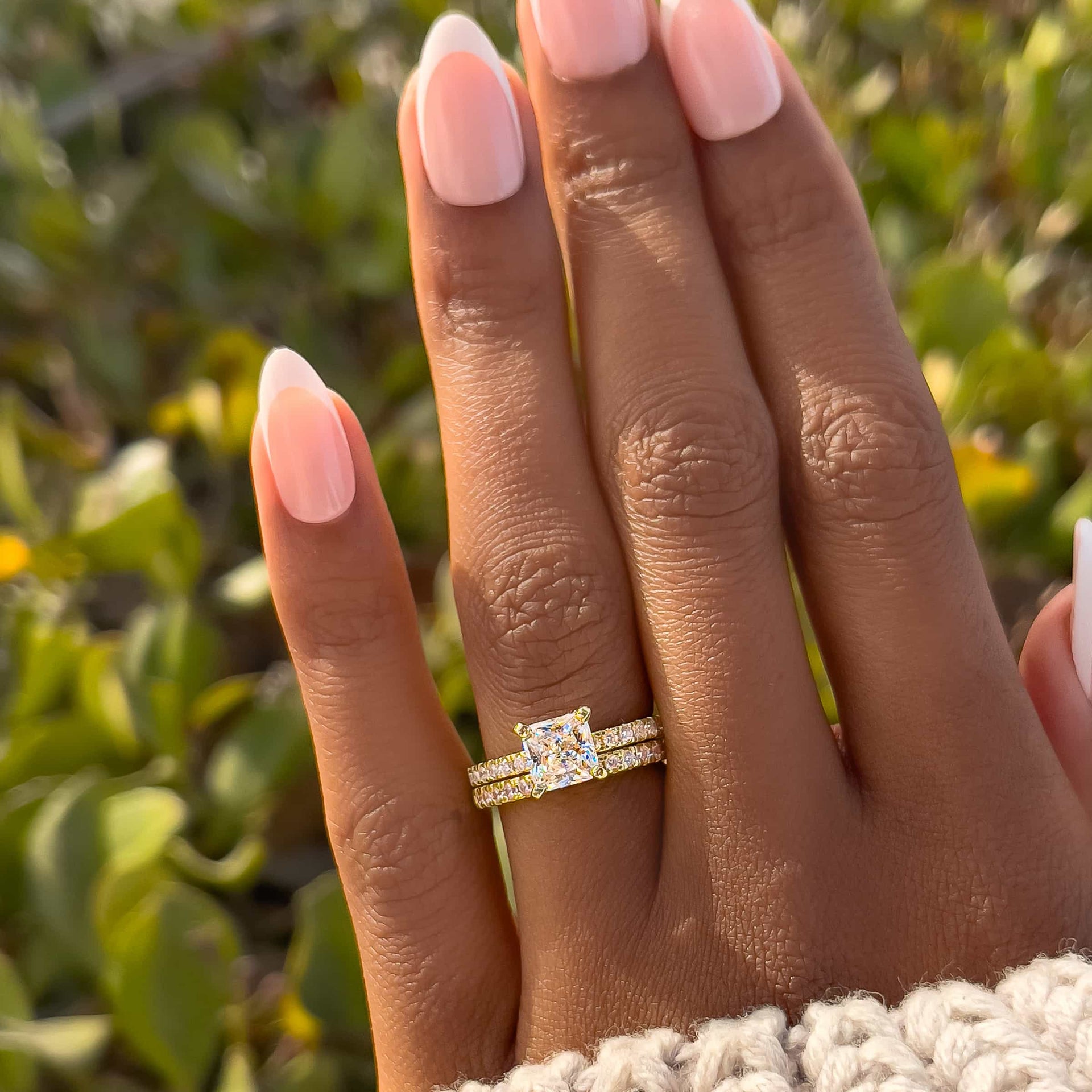 classic gold princess cut wedding ring set on model with french tip nails and cream colored sweater