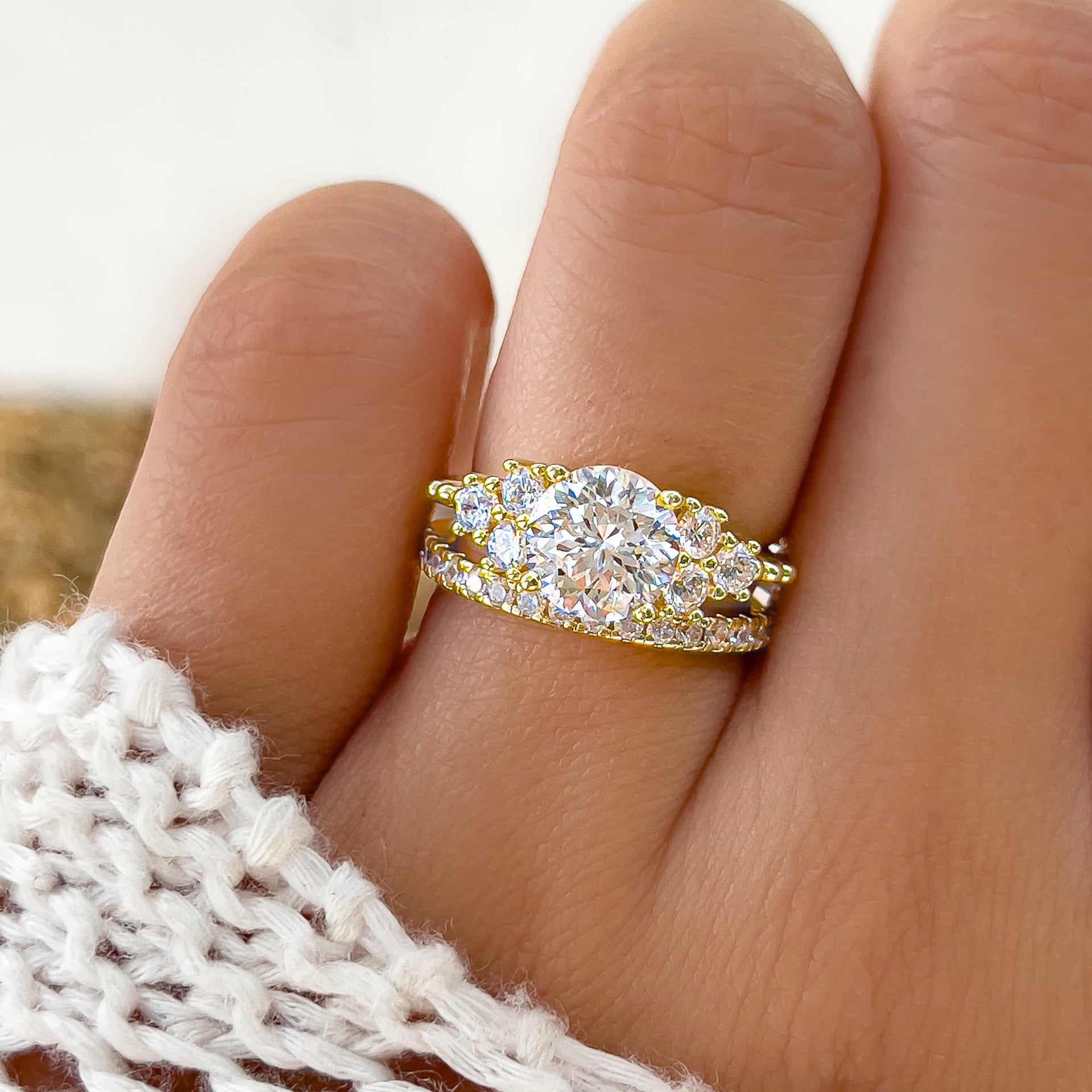 gorgeous gold wedding ring set made up of round cut engagement ring and half eternity wedding band on model with white sweater