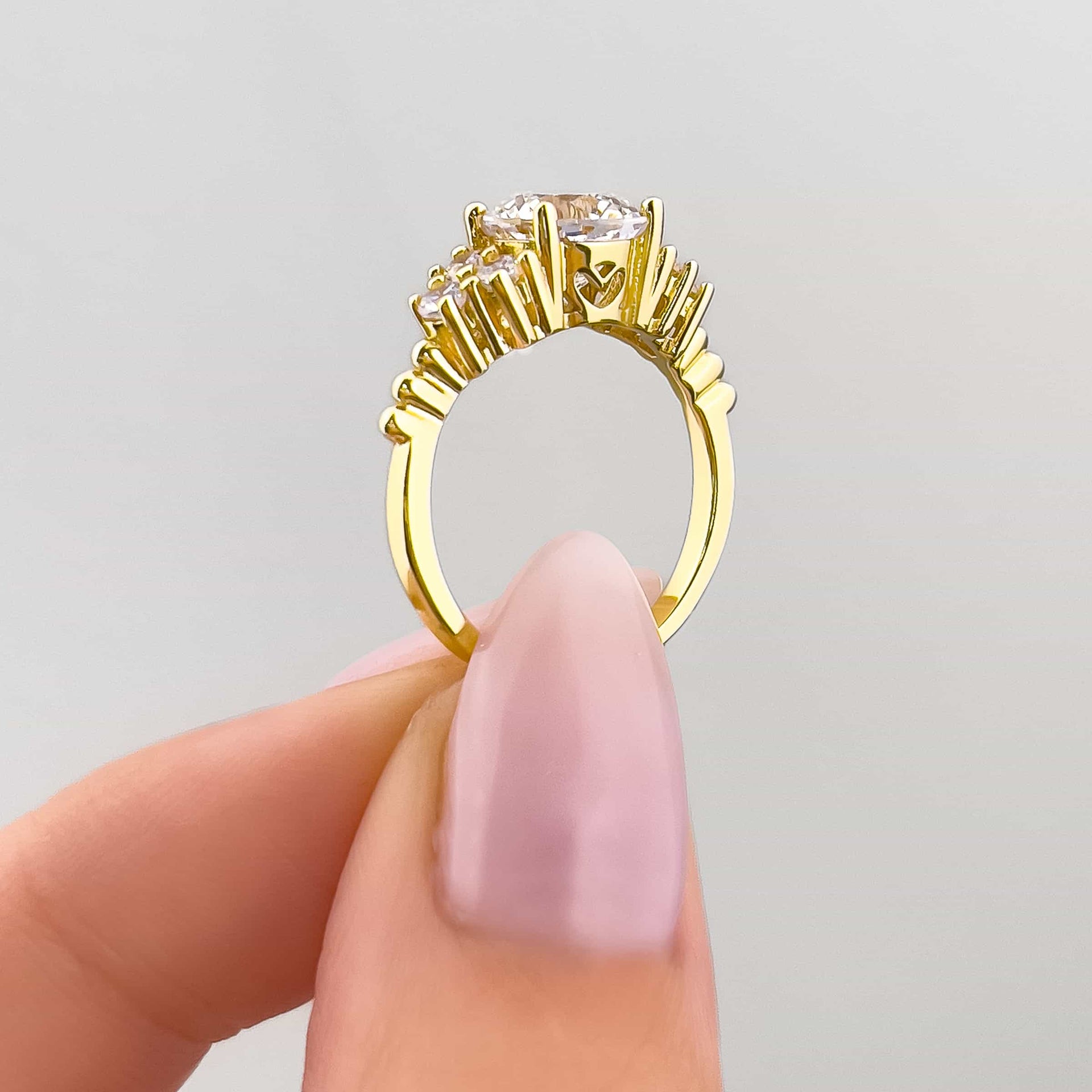 side view of gold round cut engagement ring with hidden heart detailing held by model with light pink nails