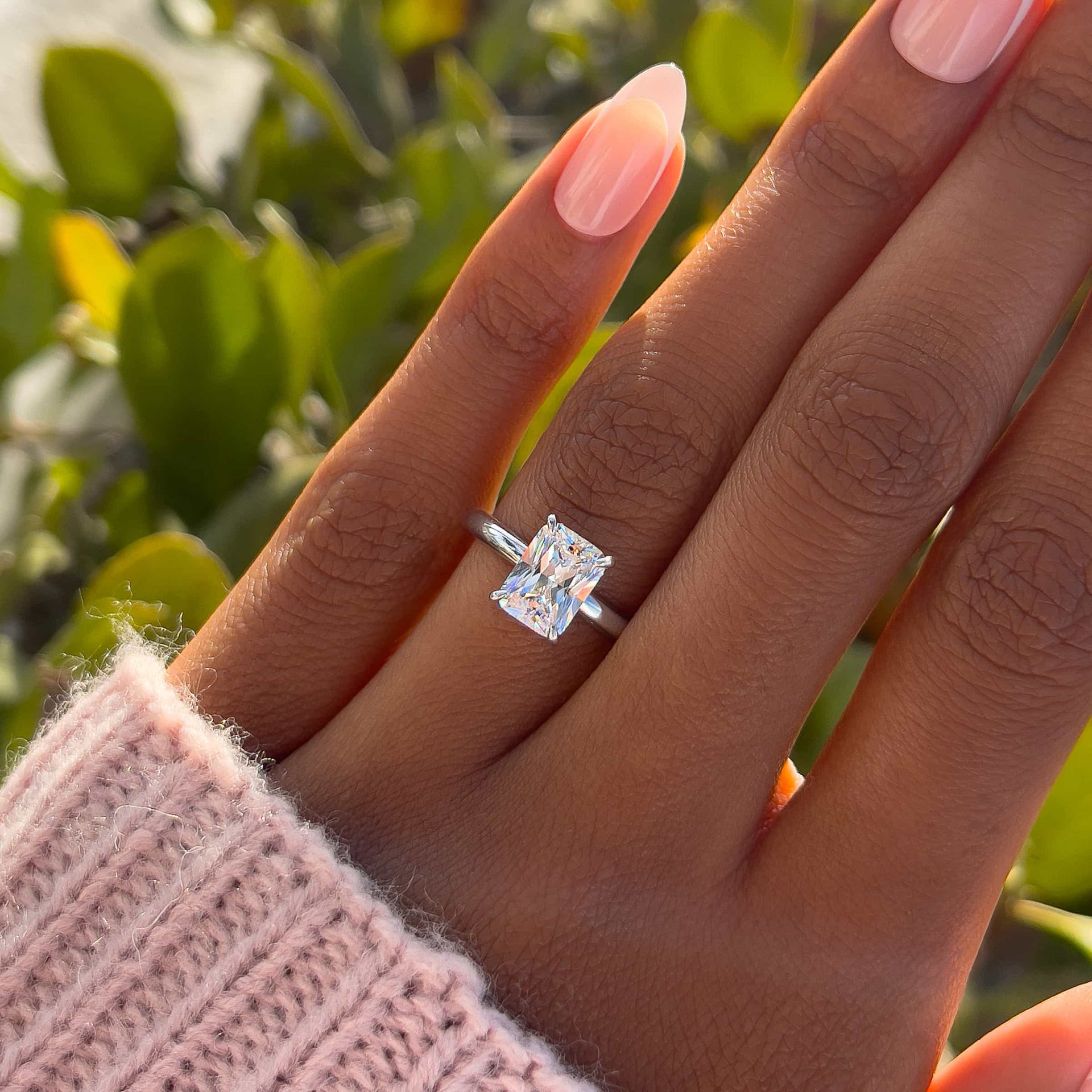 Classic silver 1.5 carat radiant cut solitaire engagement ring on model with pink sweater