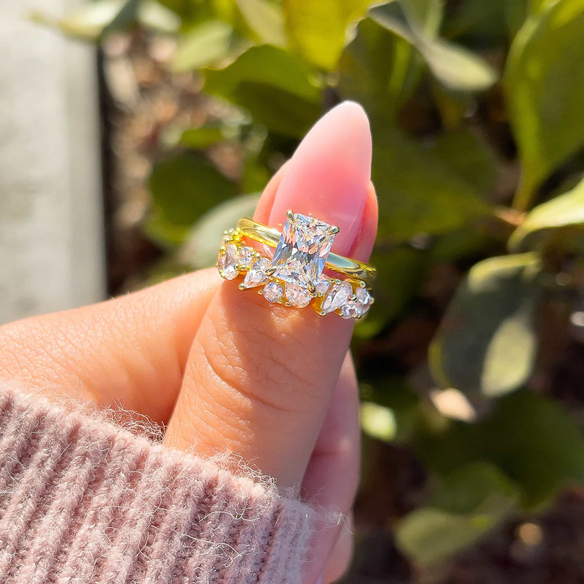 Gold 1.5 carat radiant cut solitaire paired with gold unique wedding band on model with light pink nails