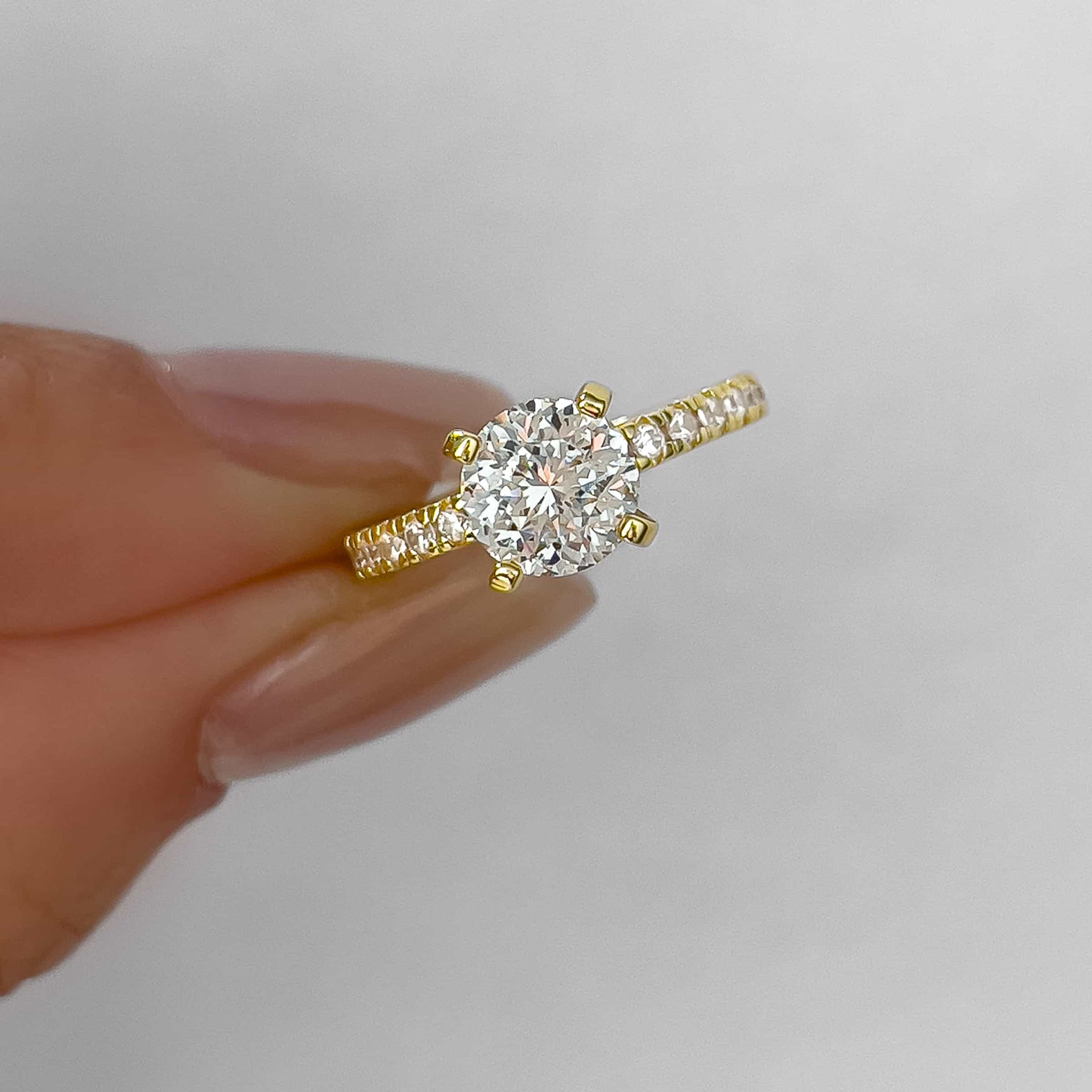 close up shot of gold 1.75 carat round cut half eternity engagement ring held by model