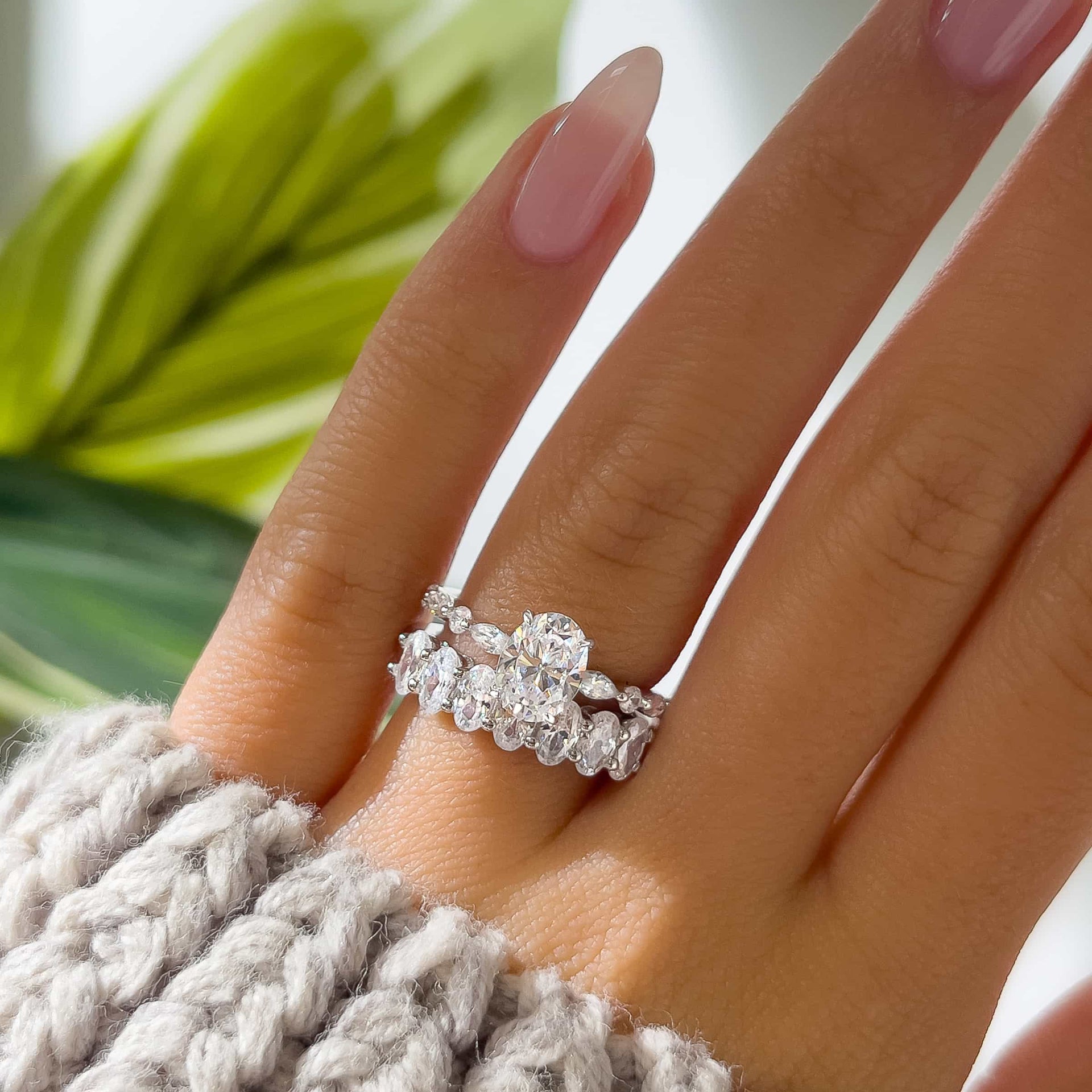 silver oval cut half eternity wedding band  with oval engagement ring on model's hand with cream sweater