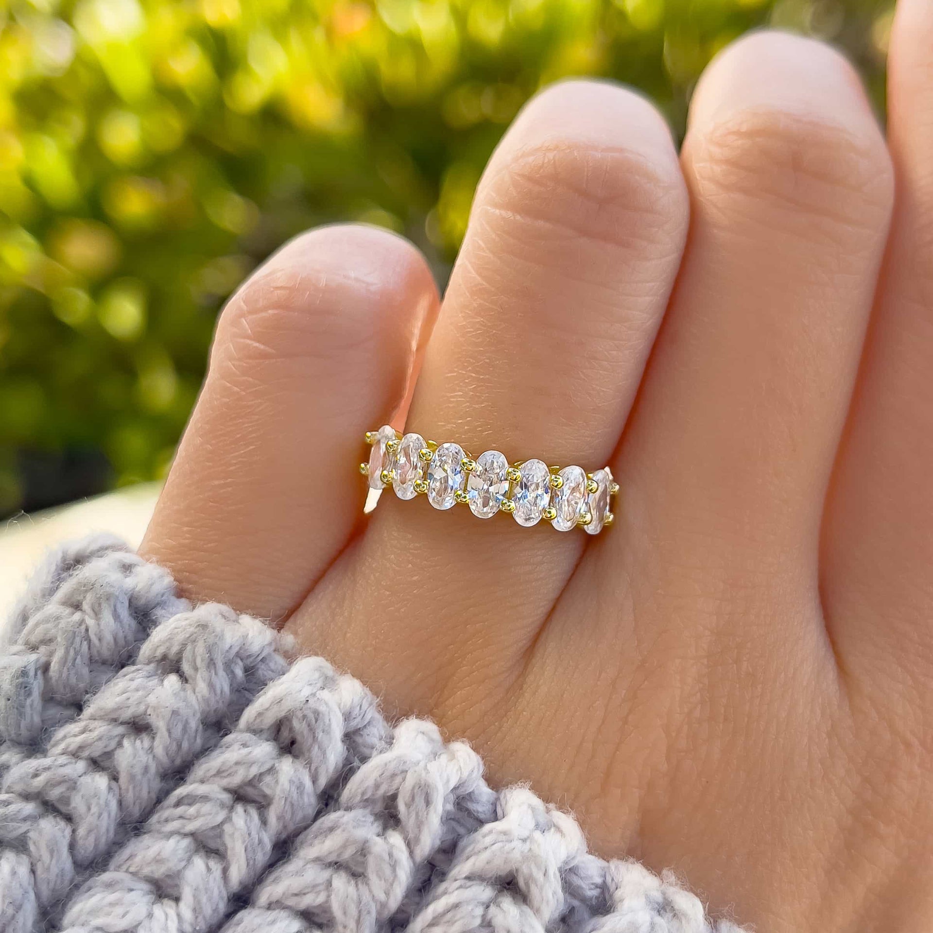 oval cut half eternity wedding band on model's hand with gray sweater